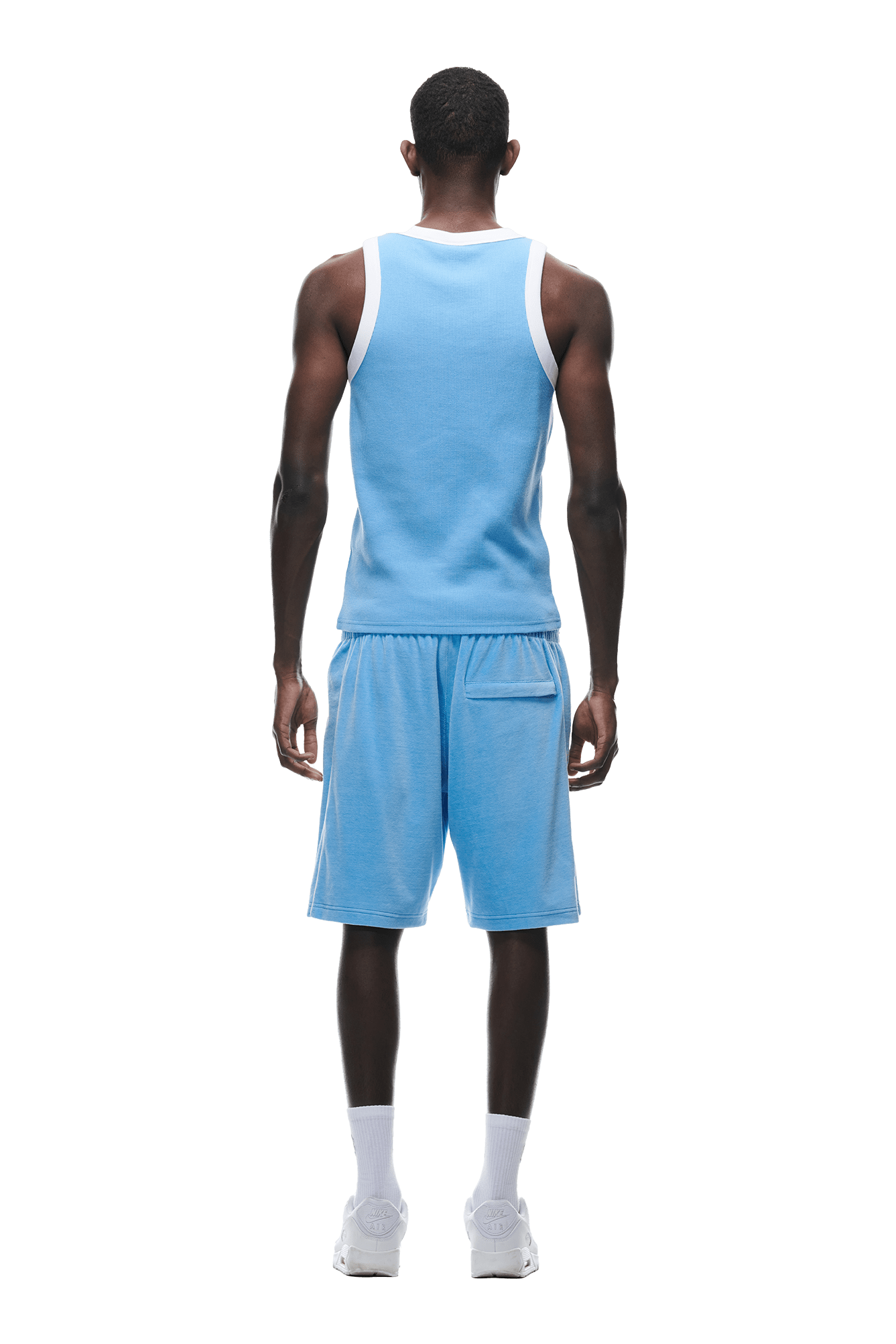 A man stands with his back to the camera, wearing the 6PM WAFFLE KNIT TANKTOP BLUE and matching blue shorts, paired with white socks and sneakers, all set against a plain white background.