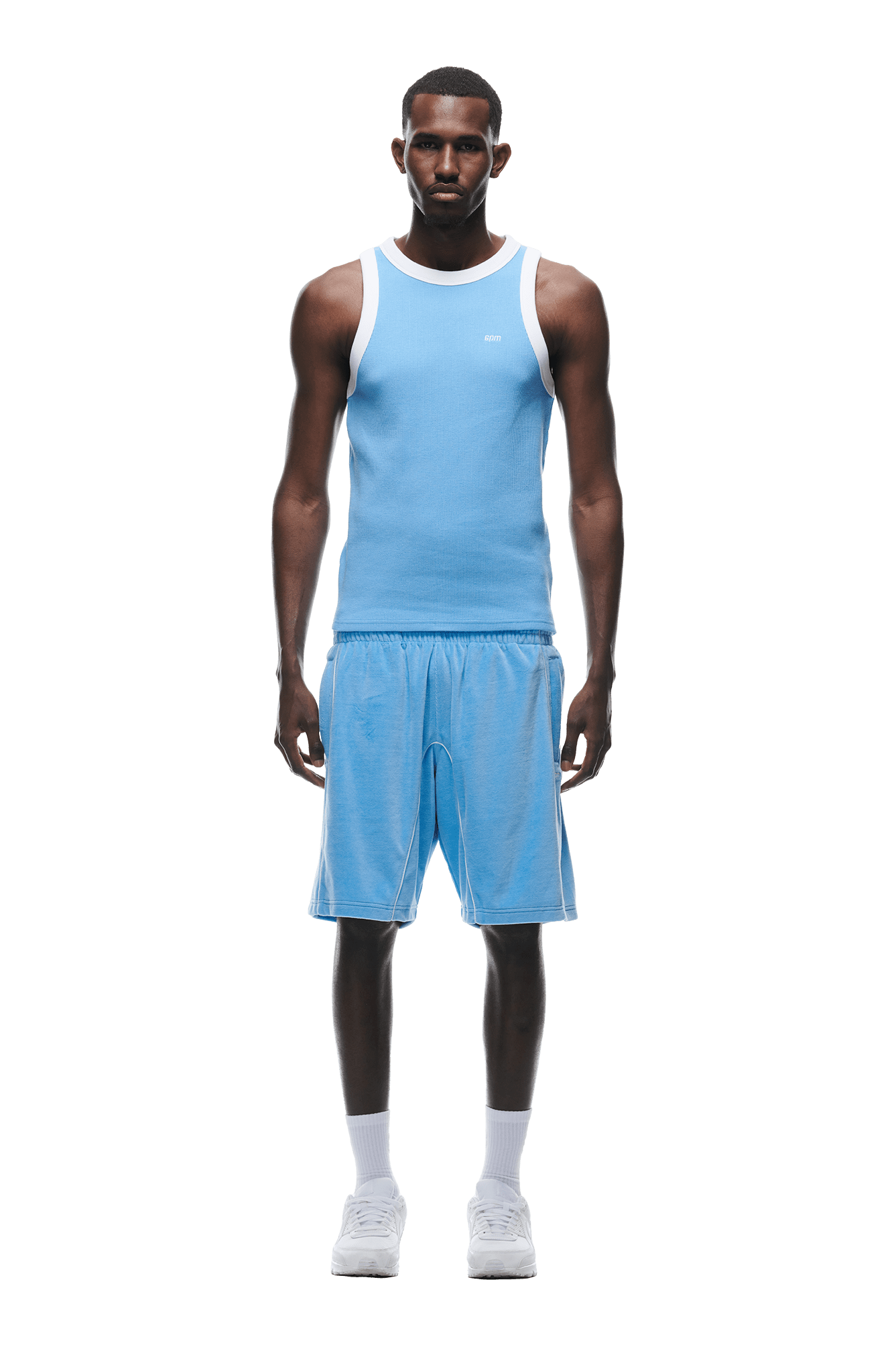 A man stands facing forward against a white background, wearing the 6PM WAFFLE KNIT TANKTOP BLUE, matching blue shorts, white crew socks, and white sneakers.