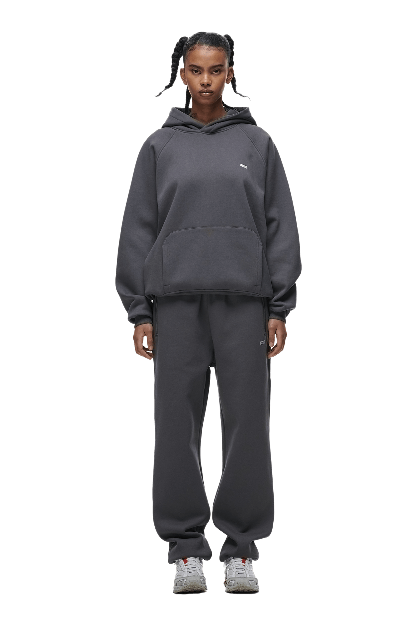 A person faces forward wearing the 6PM HOODIE ANTHRACITE, matching sweatpants, and gray sneakers. Their hair is in sectioned pigtails with white bands. The background is transparent.