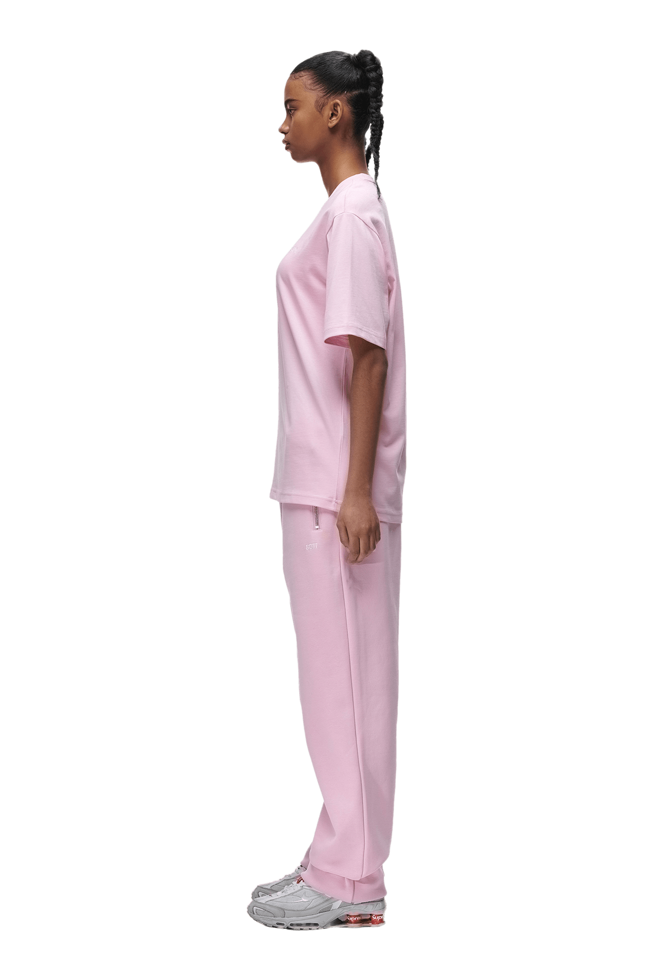 A person is shown in profile facing left, wearing the 6PM T-SHIRT BABY PINK with matching pants and gray sneakers. The background is transparent.