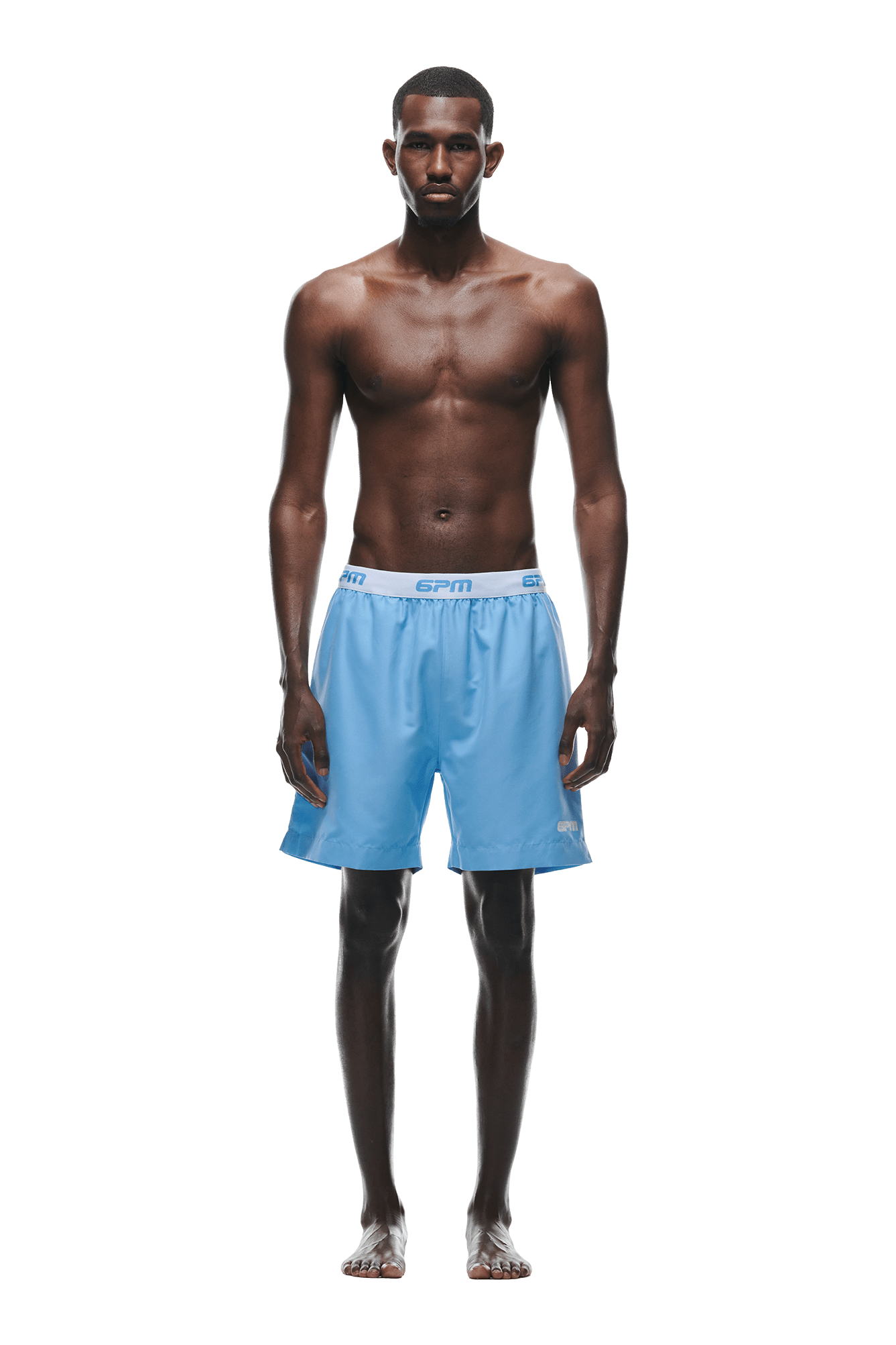 A barefoot man stands facing forward against a white background, wearing 6PM BOXER SWIM SHORTS BLUE with an elastic waistband. He is shirtless, arms relaxed at his sides.