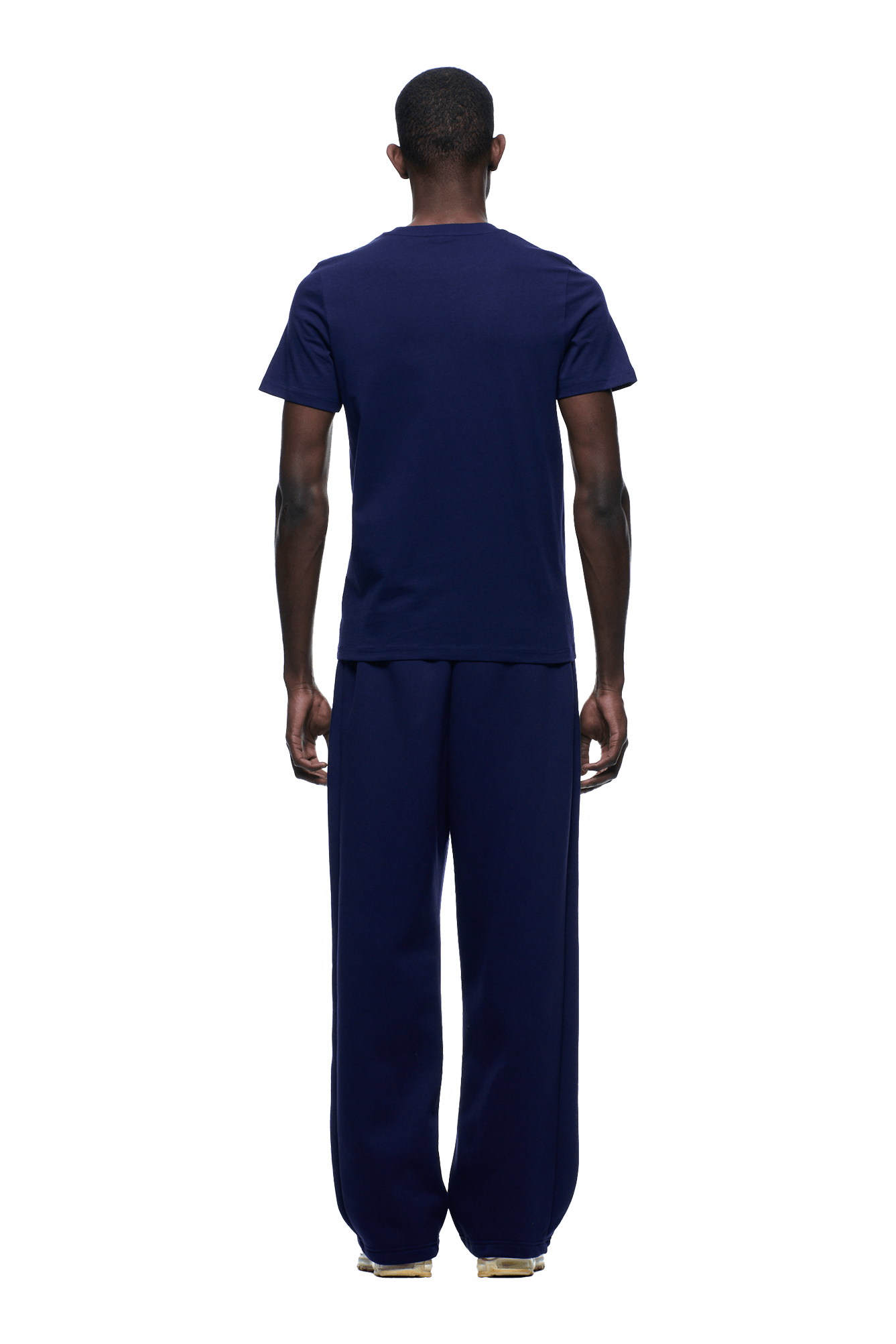 A person faces away, wearing the 6PM SLIM FIT T-SHIRT ORBIT BLUE with matching pants. The background is transparent, and their hands rest relaxed at their sides.