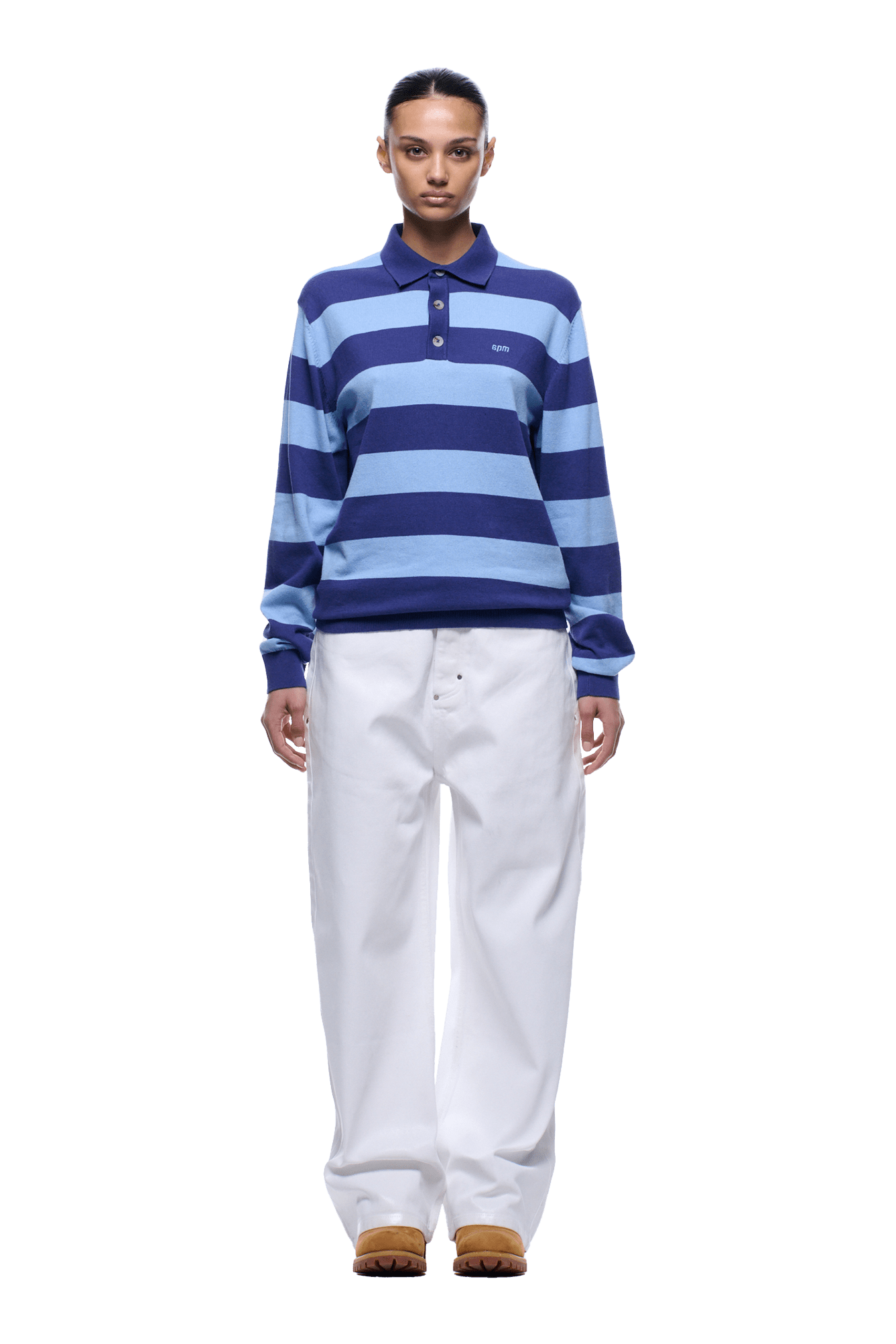 A person stands facing forward against a plain background, wearing the 6PM LS STRIPED POLO BLUE, loose white pants, and brown shoes.