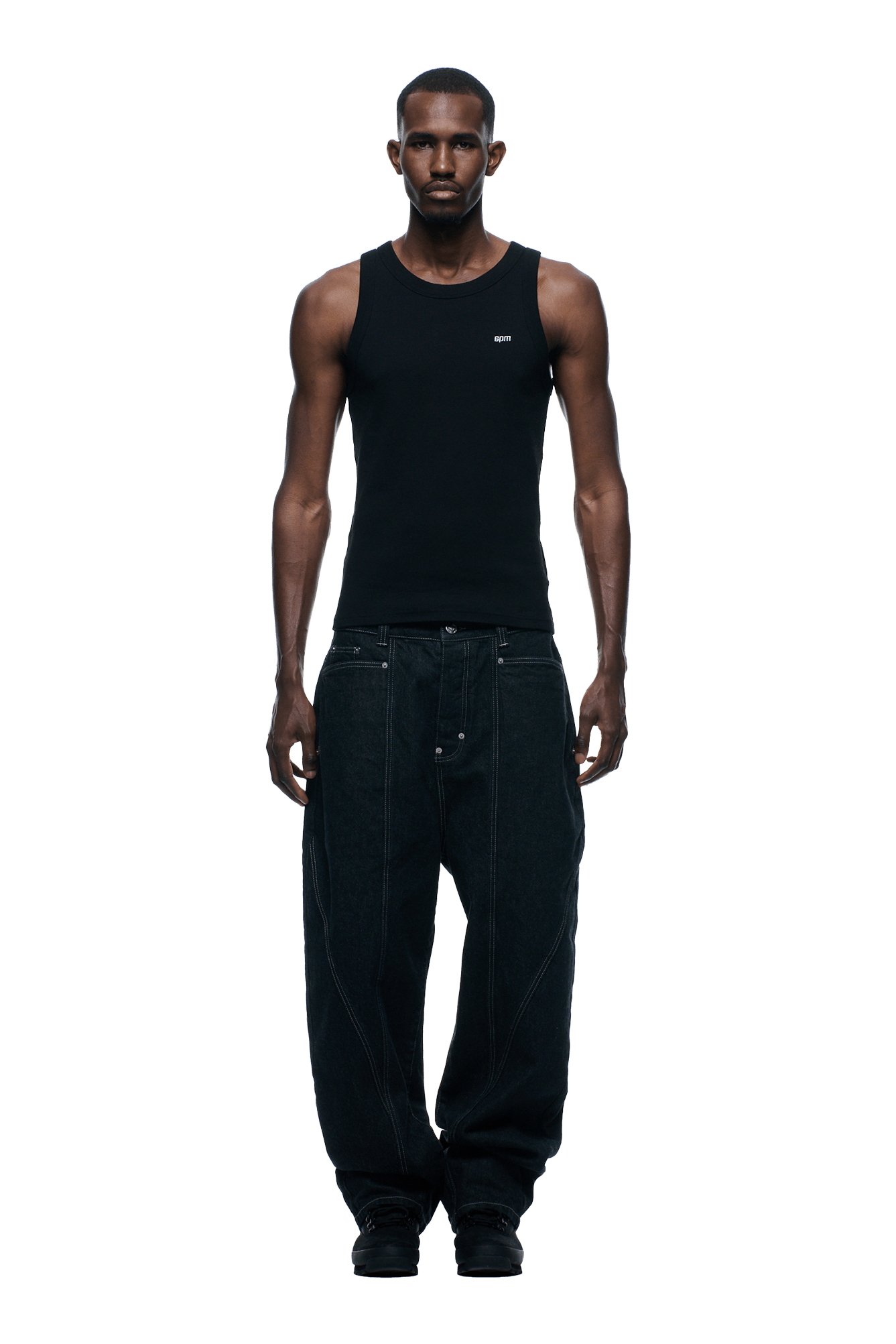 A man faces forward, wearing a fitted black tank top and loose, baggy 6PM TYPE 6 DENIM BLACK RAW jeans with black shoes. Background is transparent.