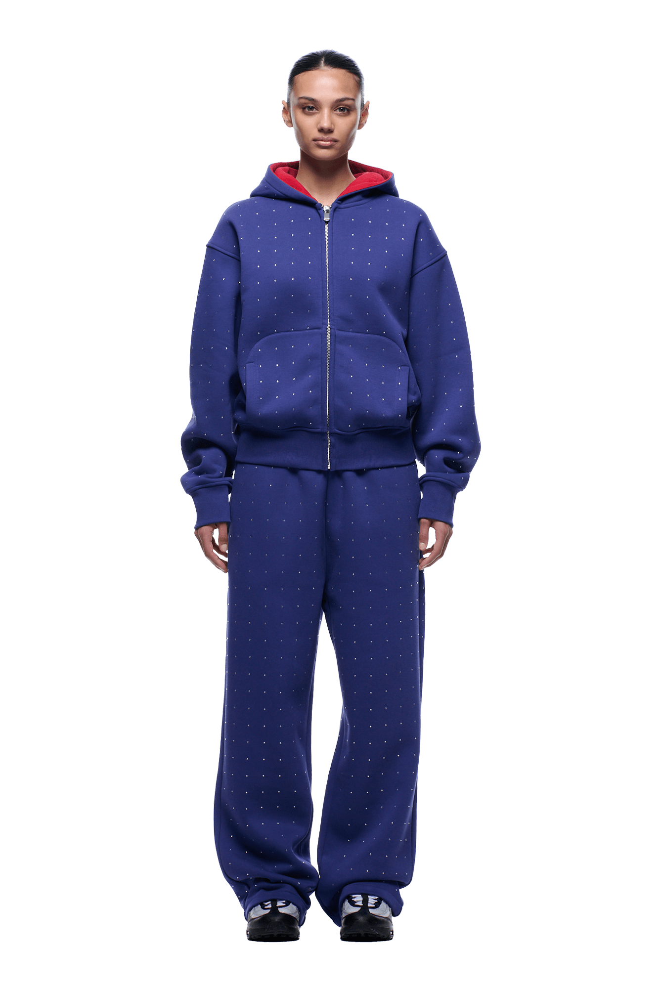A person faces forward in a 6PM RHINESTONE LETTER ZIP HOODIE BLUE with wide-leg pants featuring small white dotted lines, a red hood interior, and black sneakers. The background is transparent.