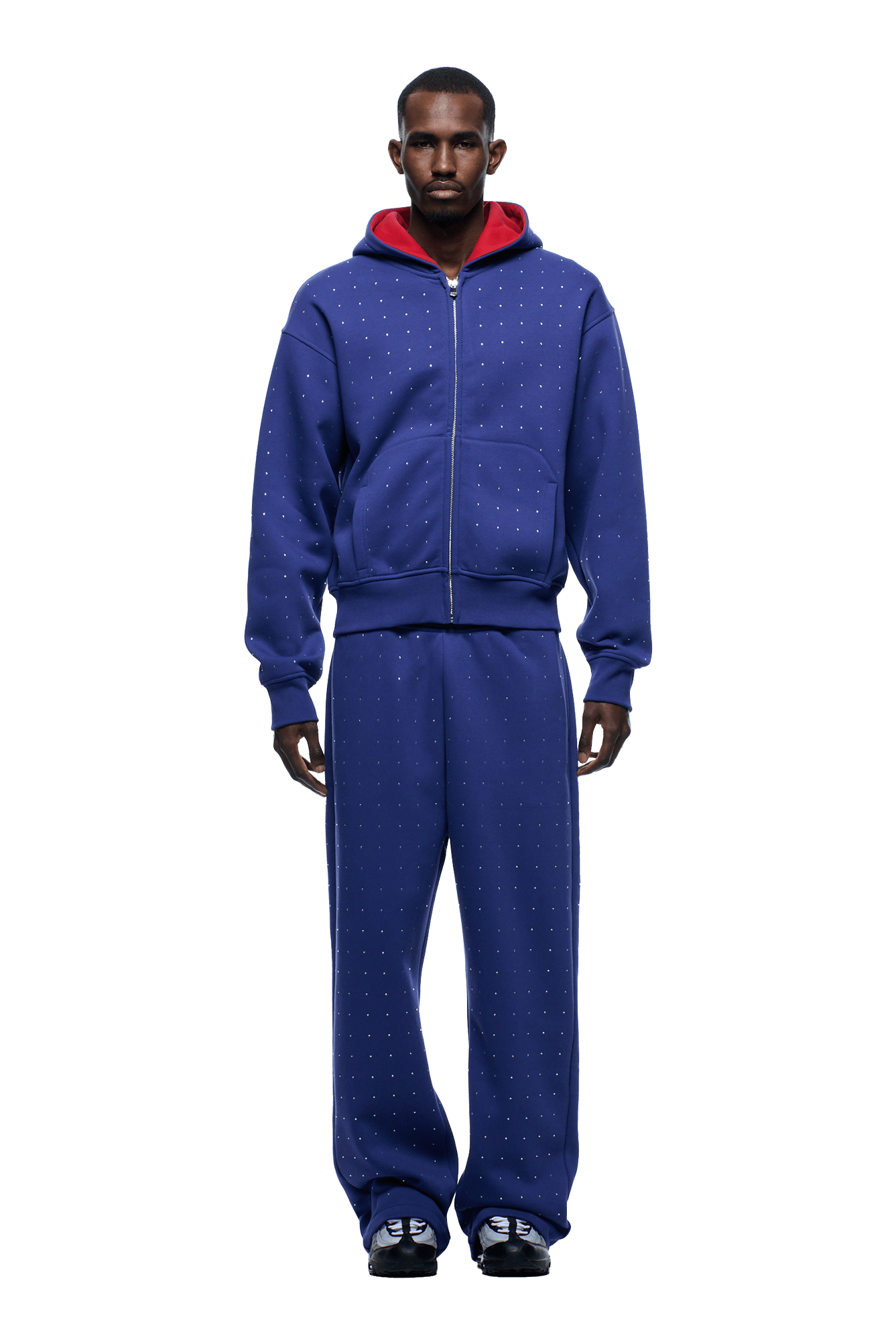 A man stands facing forward wearing the 6PM RHINESTONE LETTER ZIP HOODIE in blue with matching sweatpants, a red hood, and black sneakers. He has a neutral expression and his hands are at his sides.