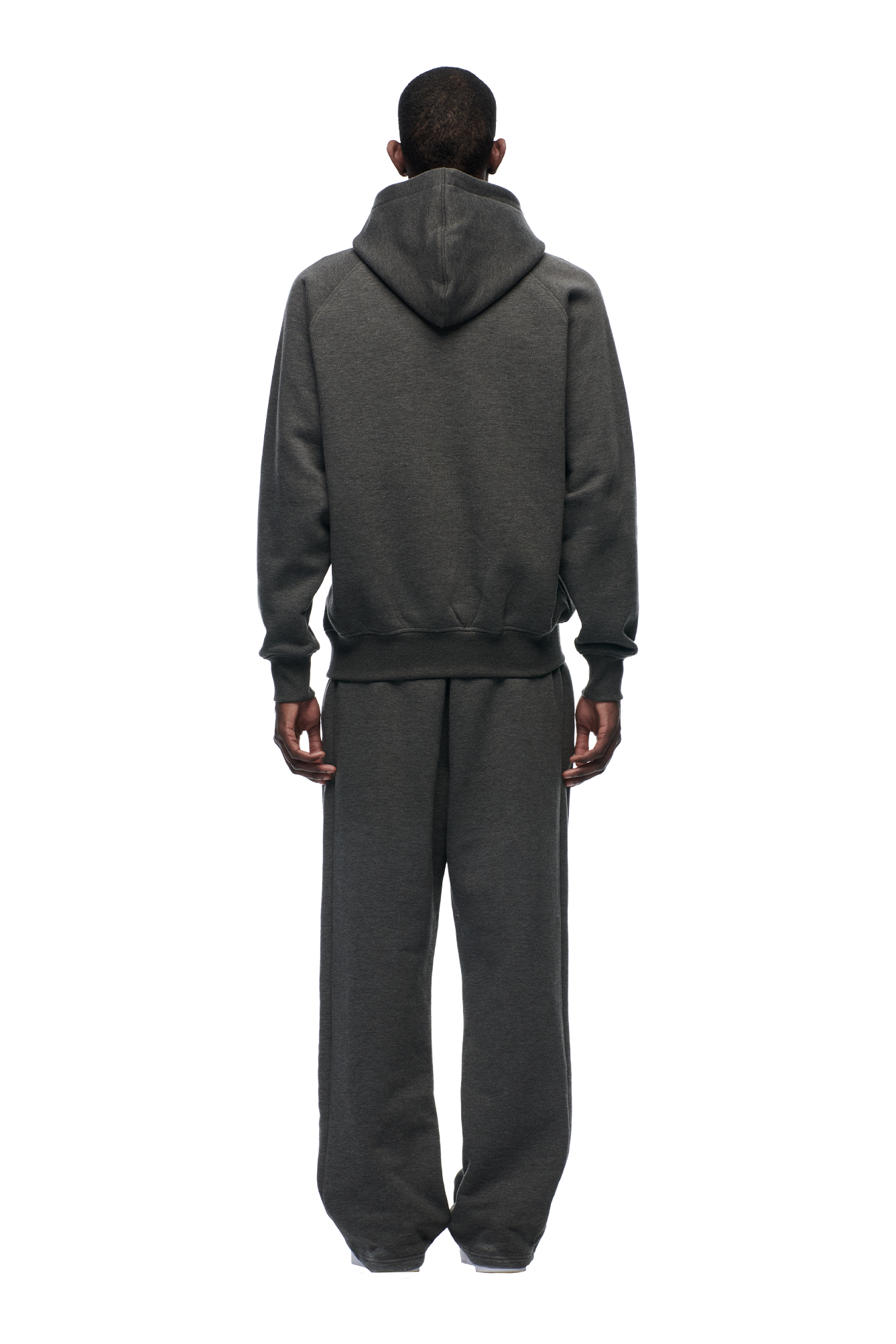A person faces away from the camera, wearing the 6PM HOODIE DARK GREY MELANGE and matching sweatpants against a plain white background.