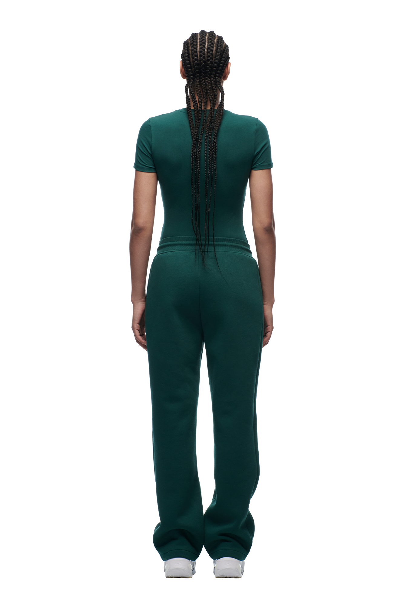 A person with long braids faces away from the camera, wearing the 6PM WMNS T-SHIRT EVERGREEN and matching green pants, against a plain white background.