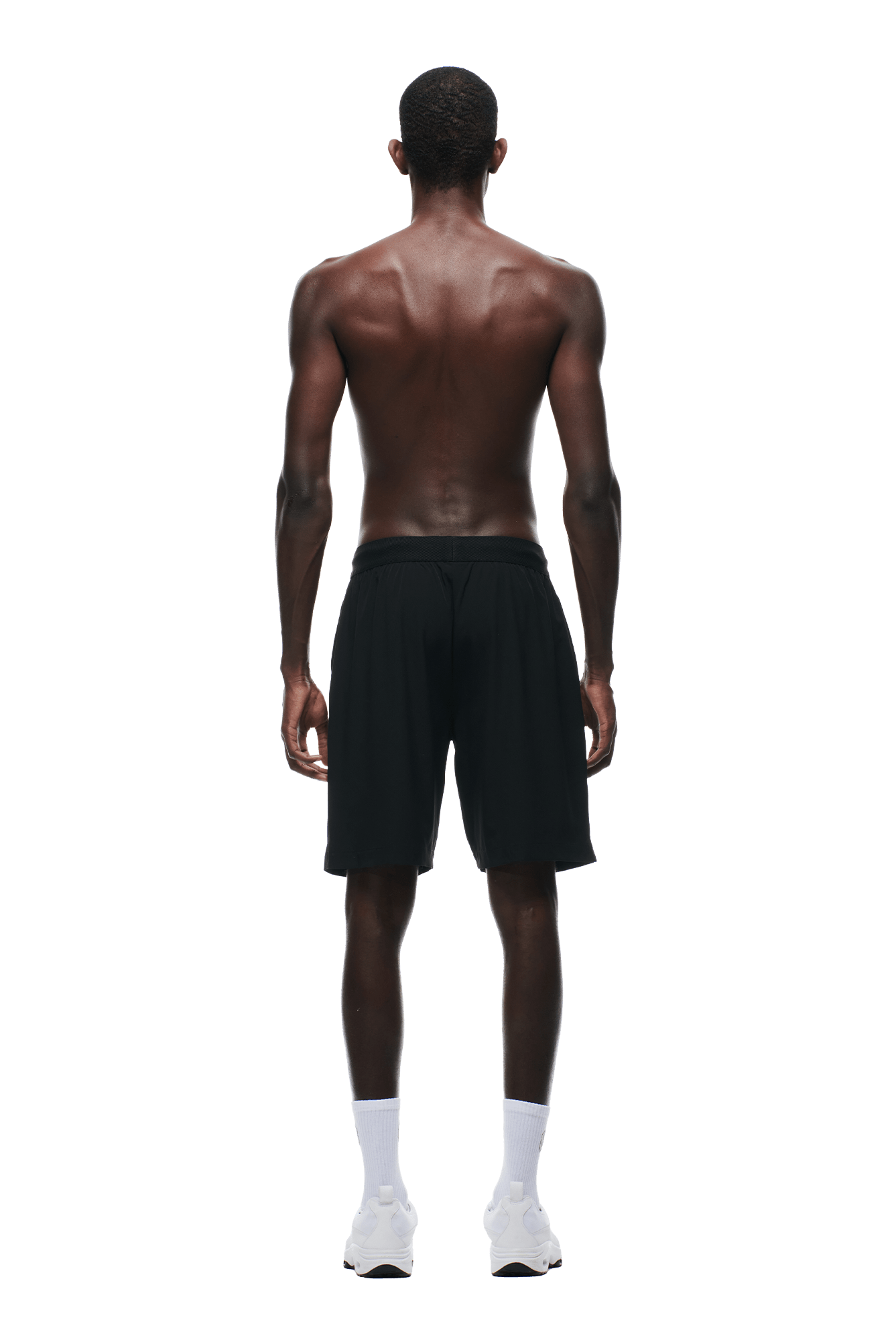 A shirtless man with dark skin, seen from behind, wears 6PM SPORTS SHORTS BLACK by 6PM, paired with white socks and white sneakers against a plain background.