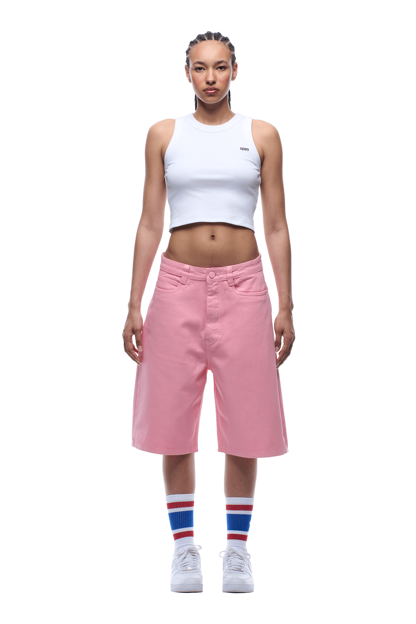 A person faces forward wearing a white sleeveless crop top, 6PM COATED DENIM SHORTS PINK, white sneakers, and white socks with blue and red stripes. The background is transparent.
