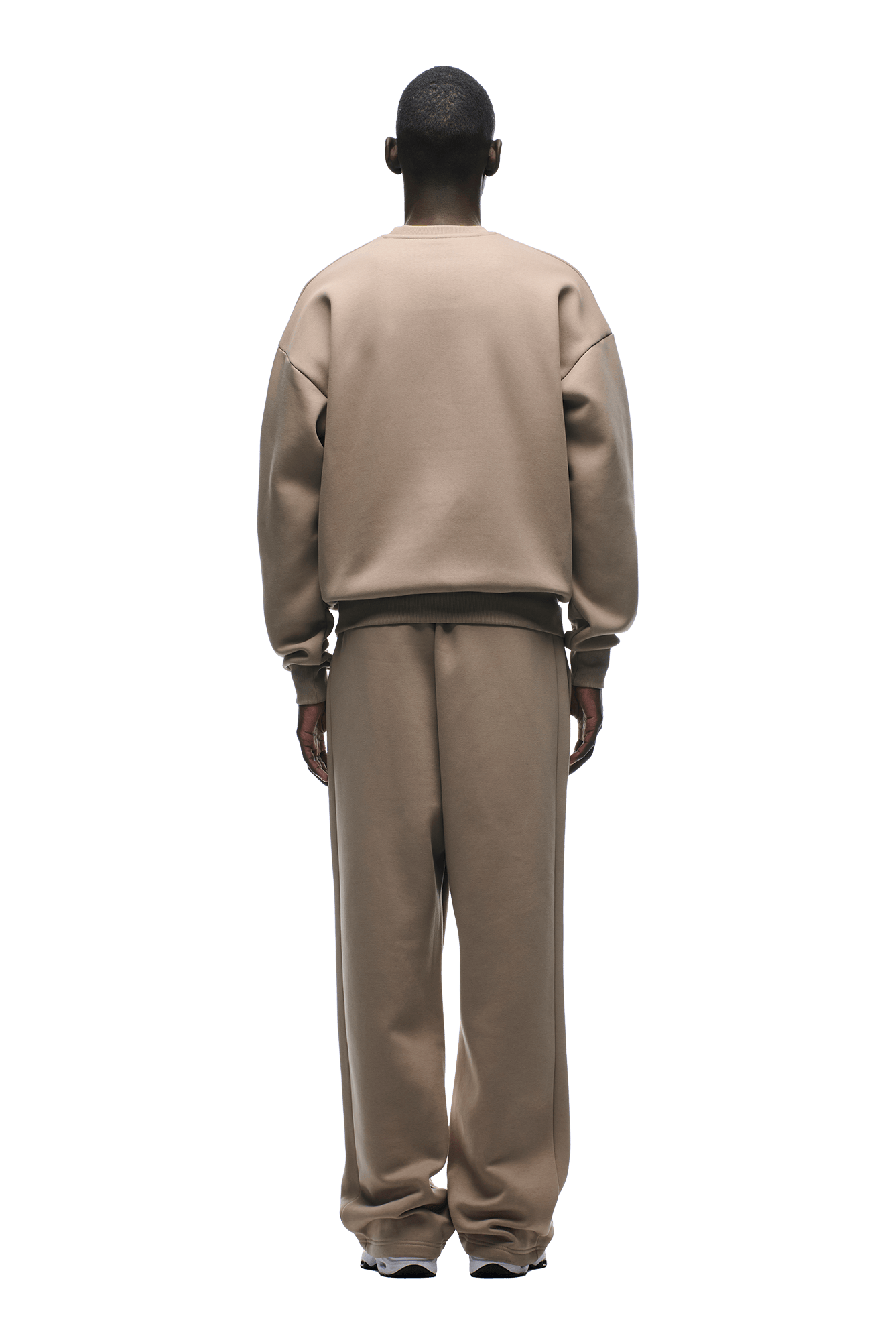 A person stands with their back to the camera in 6PM’s CREWNECK MOCCA CREAM sweatshirt, featuring a boxy fit and ribbed trims, paired with matching pants, hands at their sides against a plain background.
