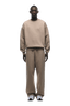 A man faces forward, wearing the 6PM CREWNECK MOCCA CREAM sweatshirt and matching sweatpants with white sneakers, set against a transparent background.