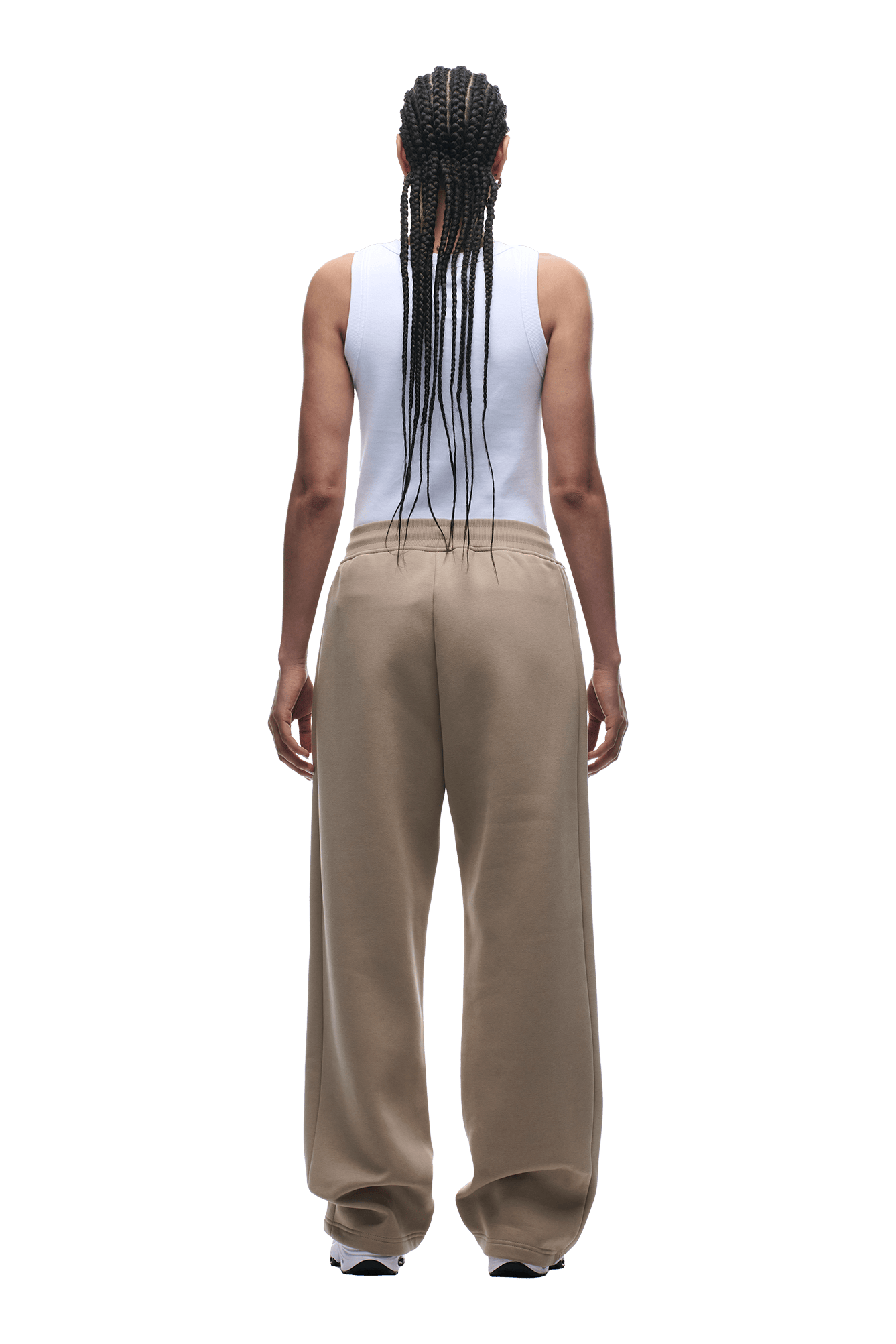A person with long braids, in a white sleeveless top and 6PM OPEN LEG JOGGER MOCCA CREAM pants, stands facing away from the camera against a plain background.