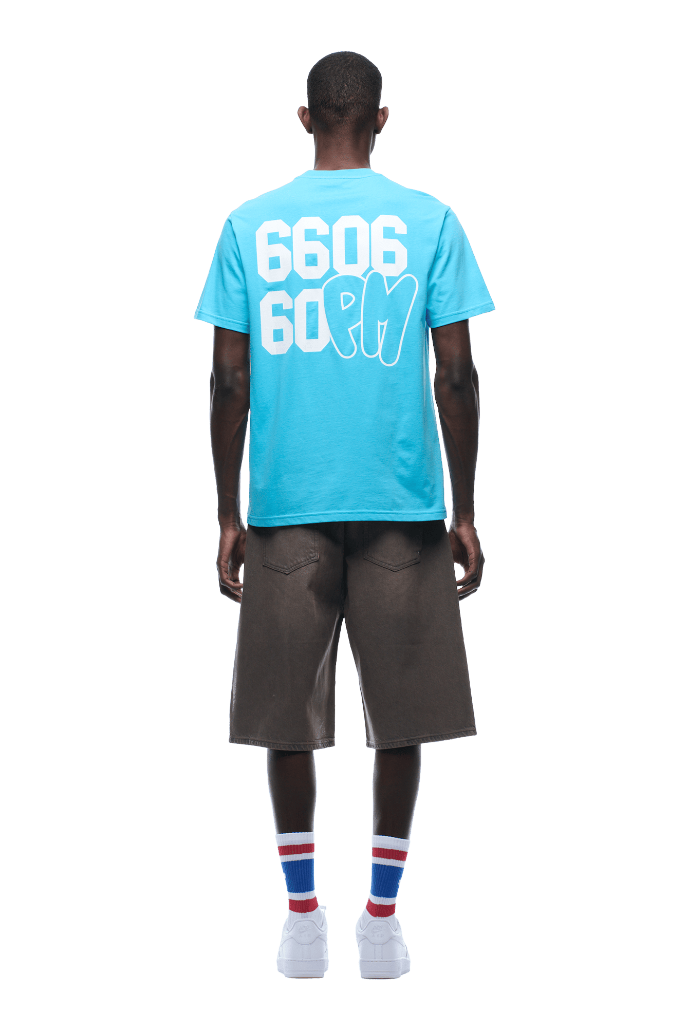 A person faces away, wearing the 6PM 660660 TEE BLUE with a back graphic, loose brown shorts, white sneakers, and white socks with red and blue stripes. Background is transparent.