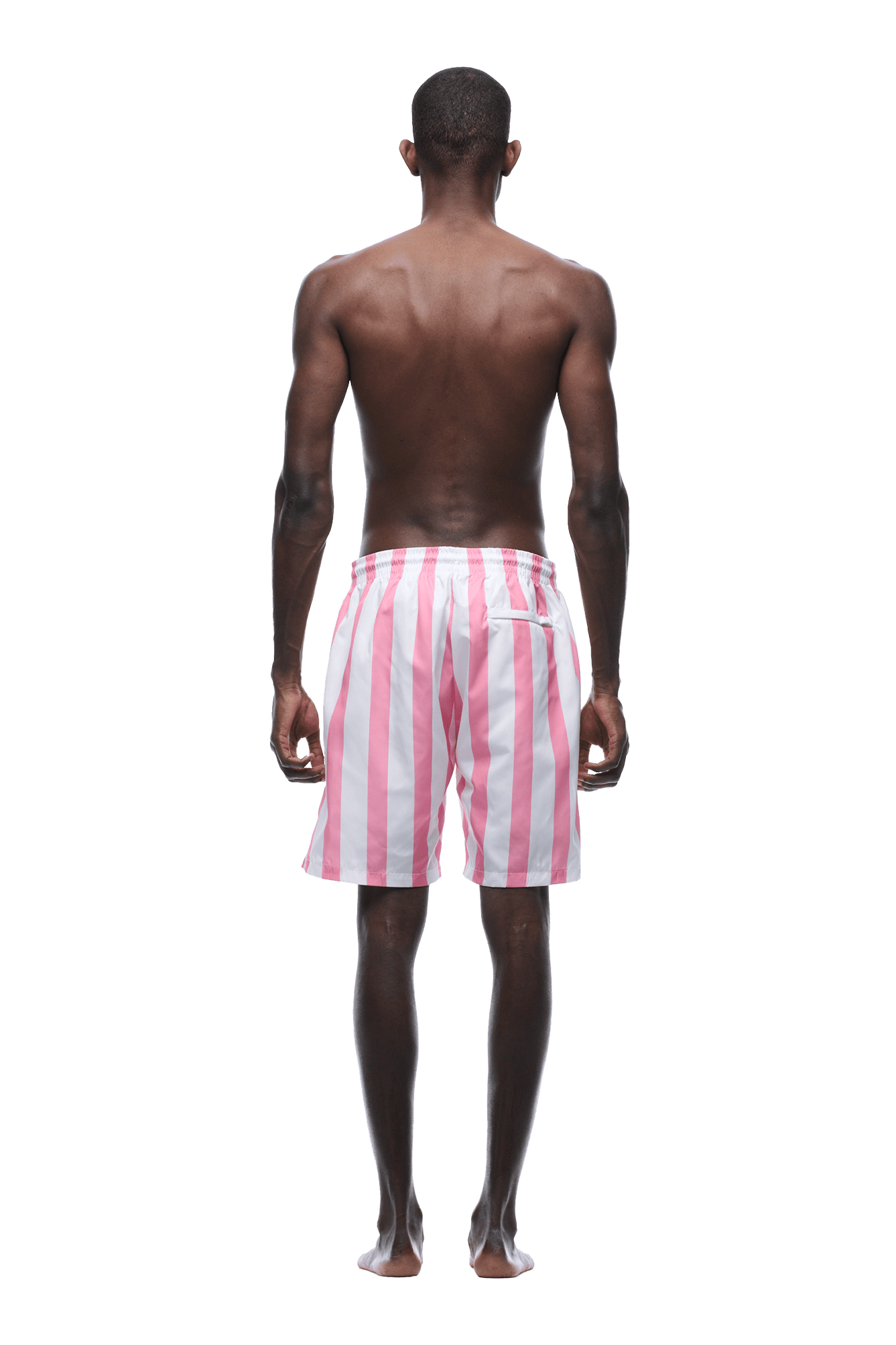 A man stands barefoot, back to the camera, wearing 6PM STRIPED SWIM SHORTS WHITE/PINK. His arms rest at his sides against a plain green background.