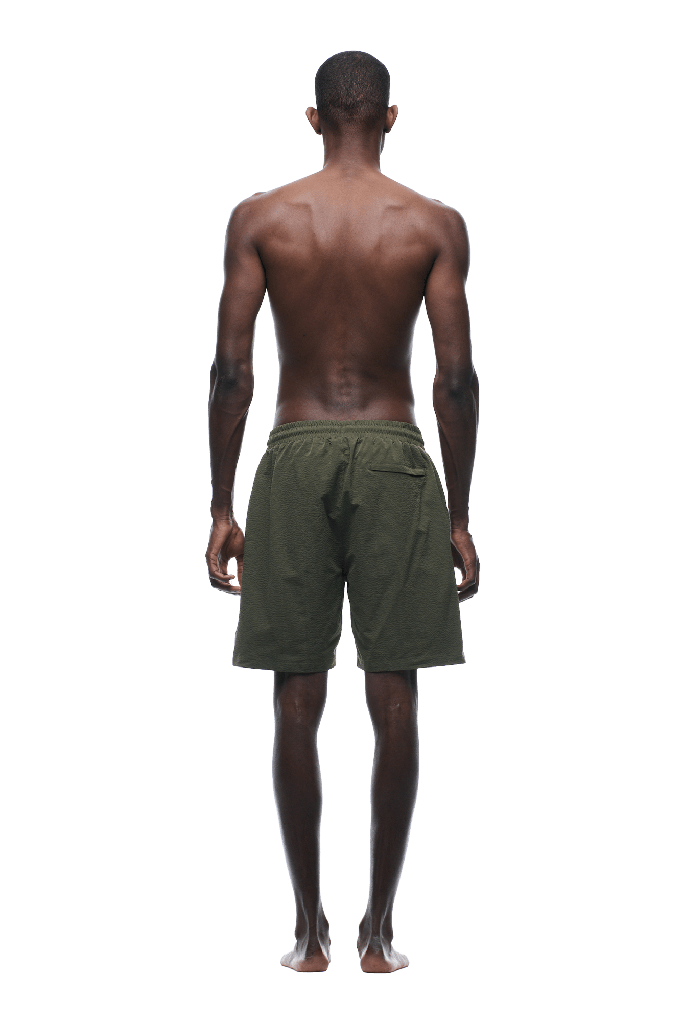 A shirtless person stands barefoot with their back to the camera, wearing 6PM SEERSUCKER SWIM SHORTS in olive against a plain background.