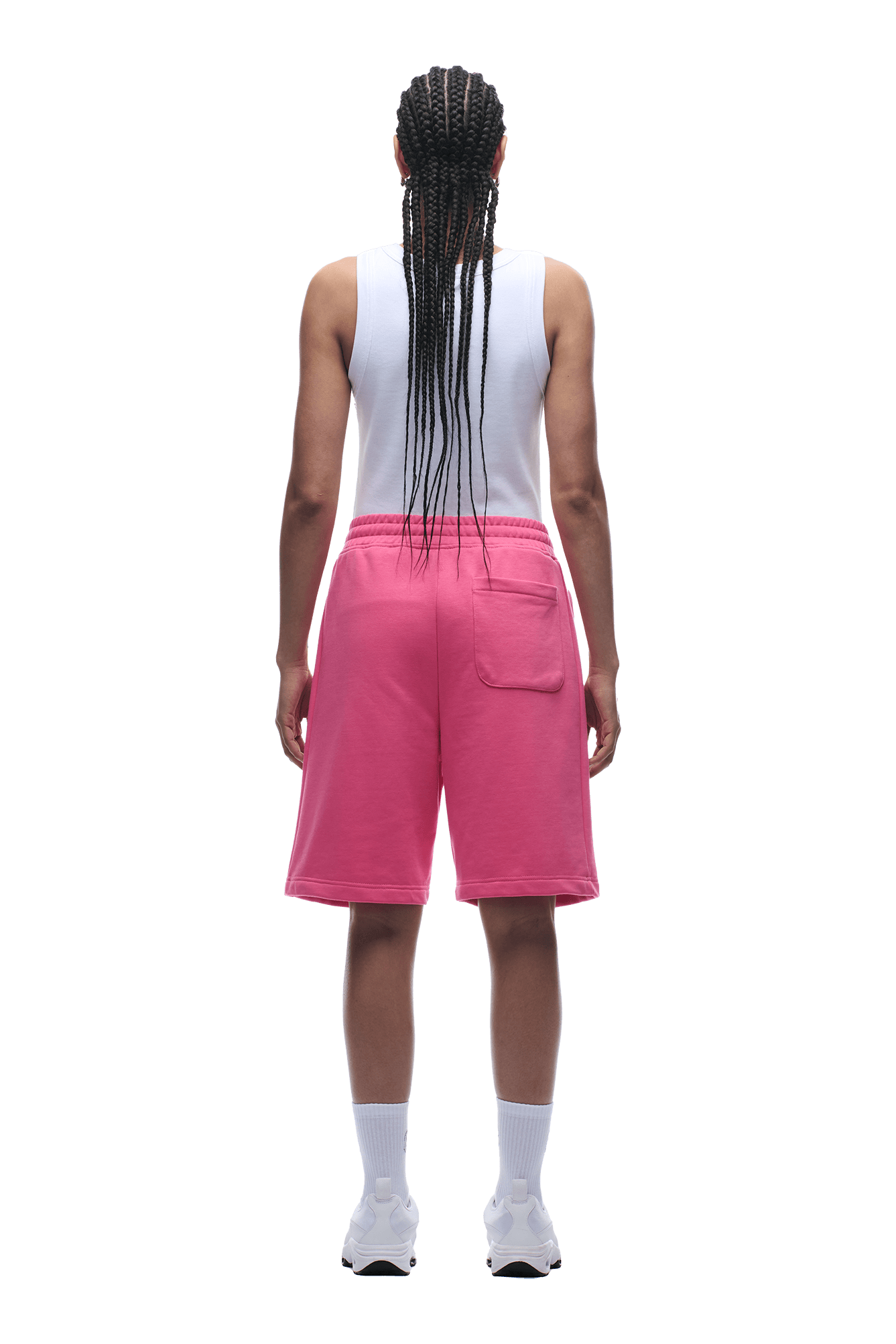 A person with long braids wears 6PM+ SHORTS HOT PINK—relaxed fit, drawstring waist—paired with a white tank top, white socks, and sneakers. Facing away from the camera against a plain background. Perfect for lounging.