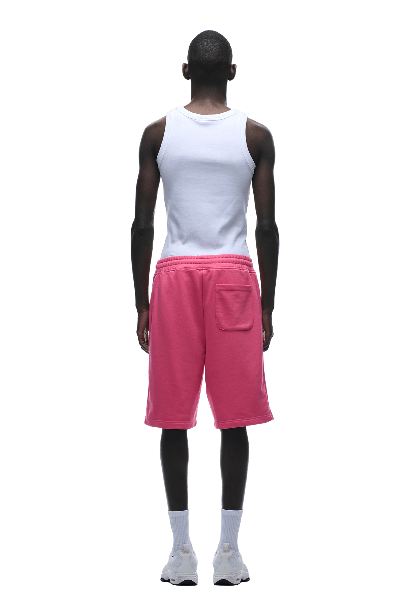 A man stands facing away, wearing 6PM+ SHORTS HOT PINK with a drawstring waist and back pocket, a white sleeveless tank top, white socks, and sneakers—ideal loungewear shown on a transparent background.