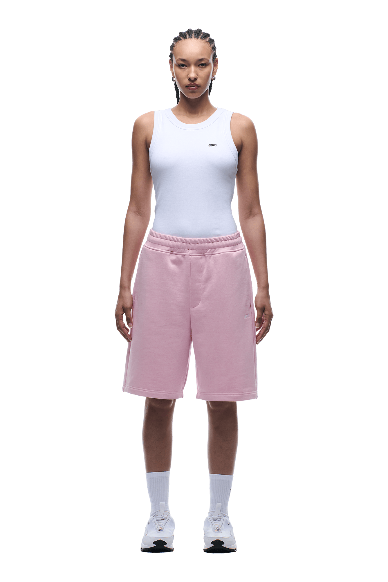 A person faces forward, wearing a white sleeveless top and 6PM+ SHORTS BABY PINK by 6PM—relaxed fit, light pink, knee-length shorts with a drawstring waist—paired with white socks and sneakers on a transparent background.