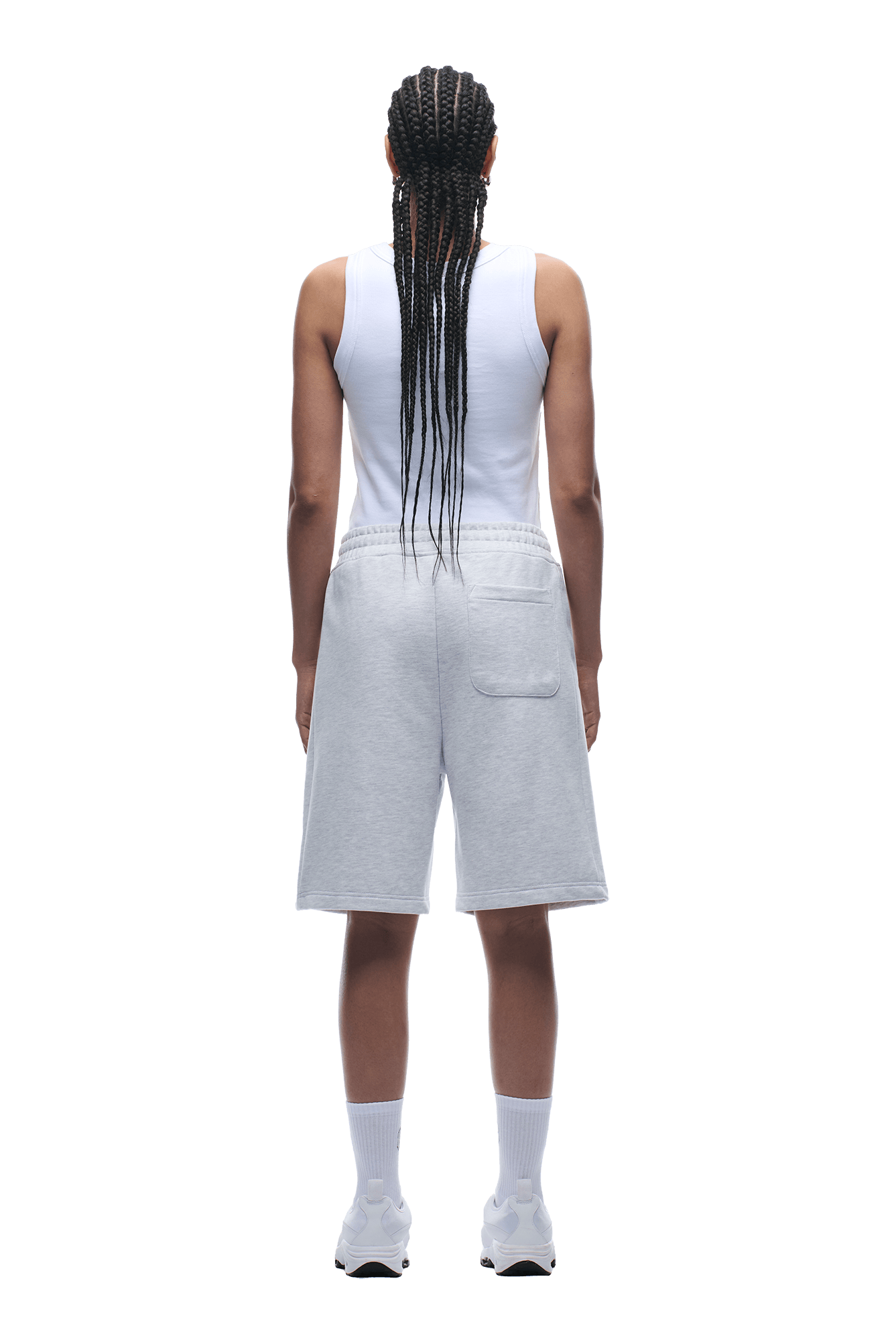 A person with long braids stands facing away, wearing a white sleeveless top and 6PM 6PM+ SHORTS LIGHT GREY—relaxed fit, knee-length with a drawstring waist—paired with white socks and sneakers against a transparent background.