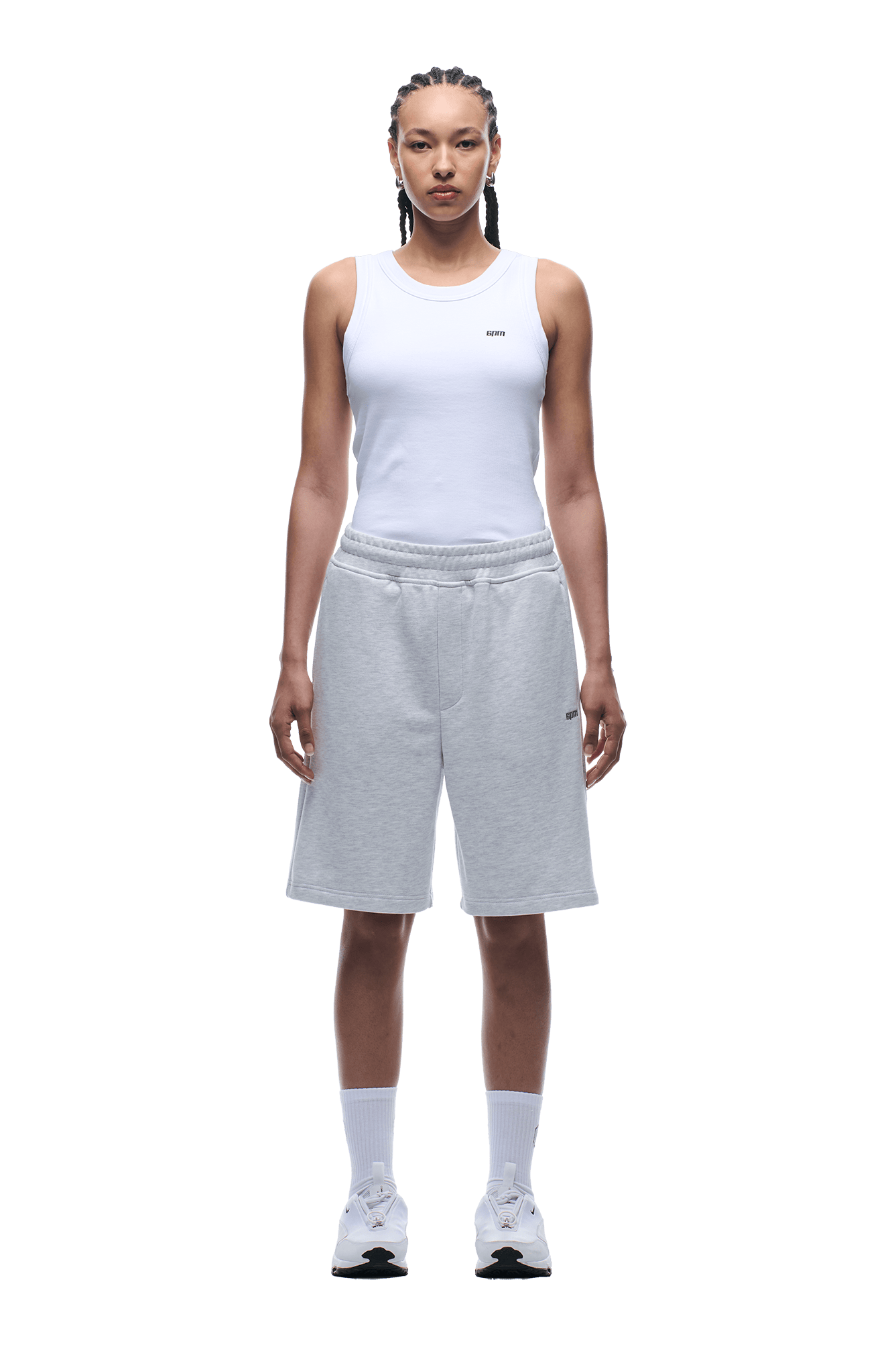 A person stands facing forward, wearing a white sleeveless tank top with 6PM 6PM+ SHORTS LIGHT GREY—relaxed fit, knee-length with a drawstring waist—plus white crew socks and sneakers, set against a plain background.