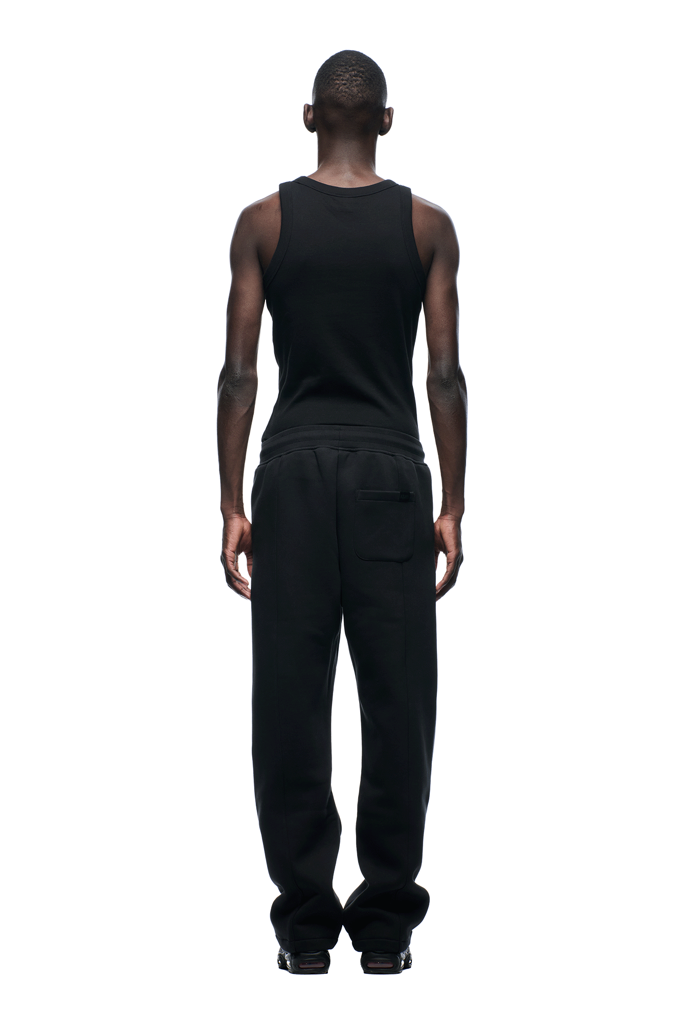 A man faces away from the camera, wearing a black tank top and 6PM+ SLIM FIT JOGGER FADED BLACK pants by 6PM, both featuring a tapered fit, set against a plain white background.