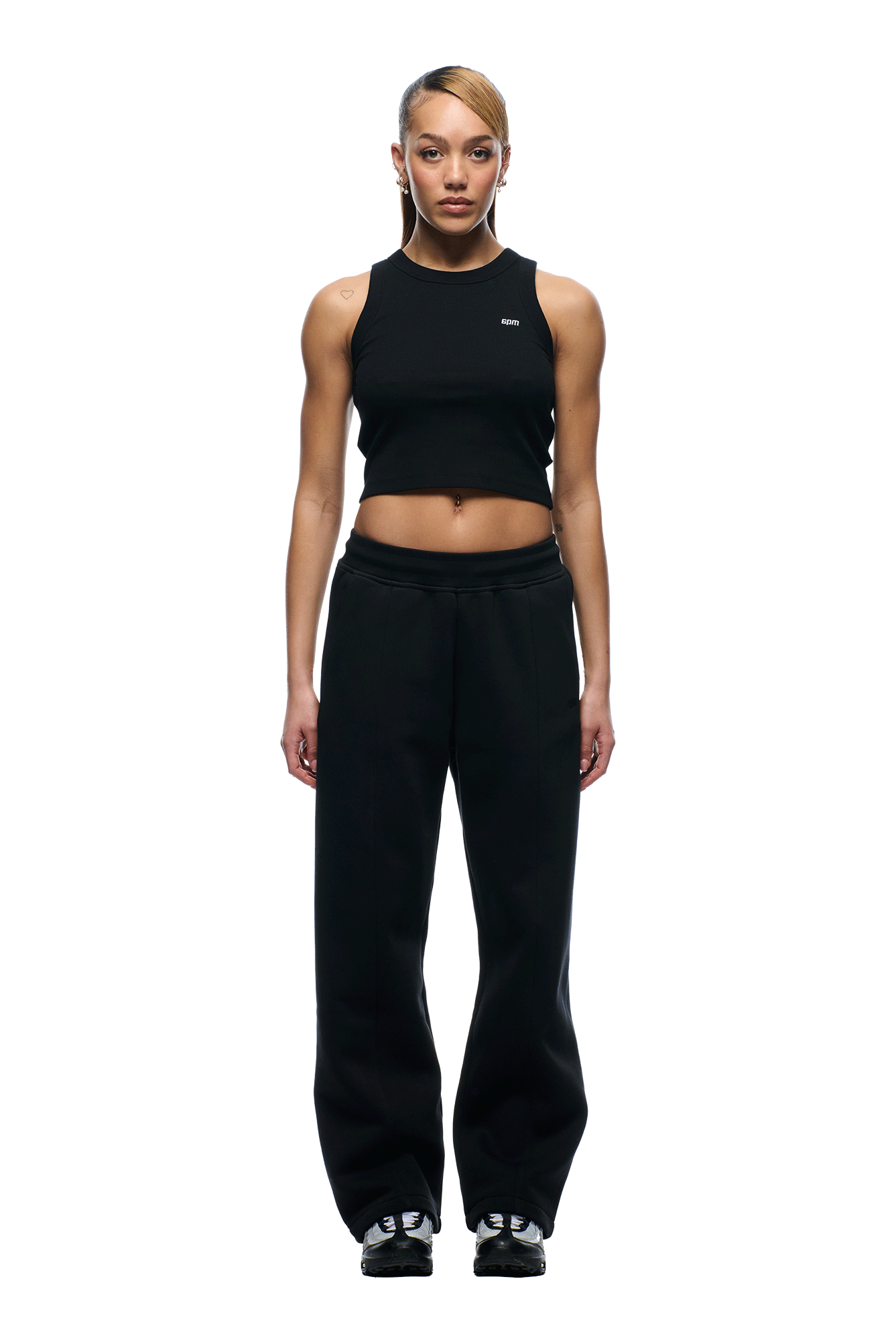 A person stands facing forward in a sleeveless black crop top and 6PM+ SLIM FIT JOGGER FADED BLACK pants by 6PM, paired with black sneakers against a plain white background.