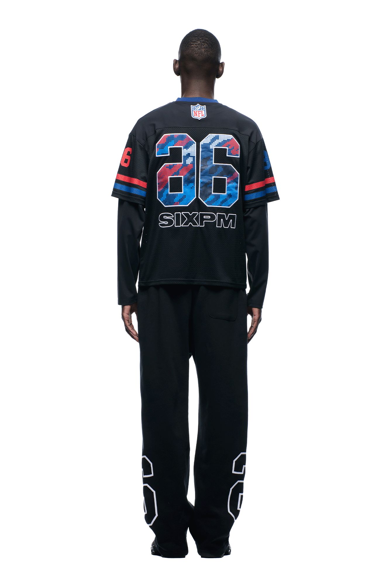 A person stands facing away, wearing the 6PM NFL LAYERED MESH LONGSLEEVE BLACK jersey with blue and red accents and the number 26, plus black pants also displaying the number 26 on the lower legs.