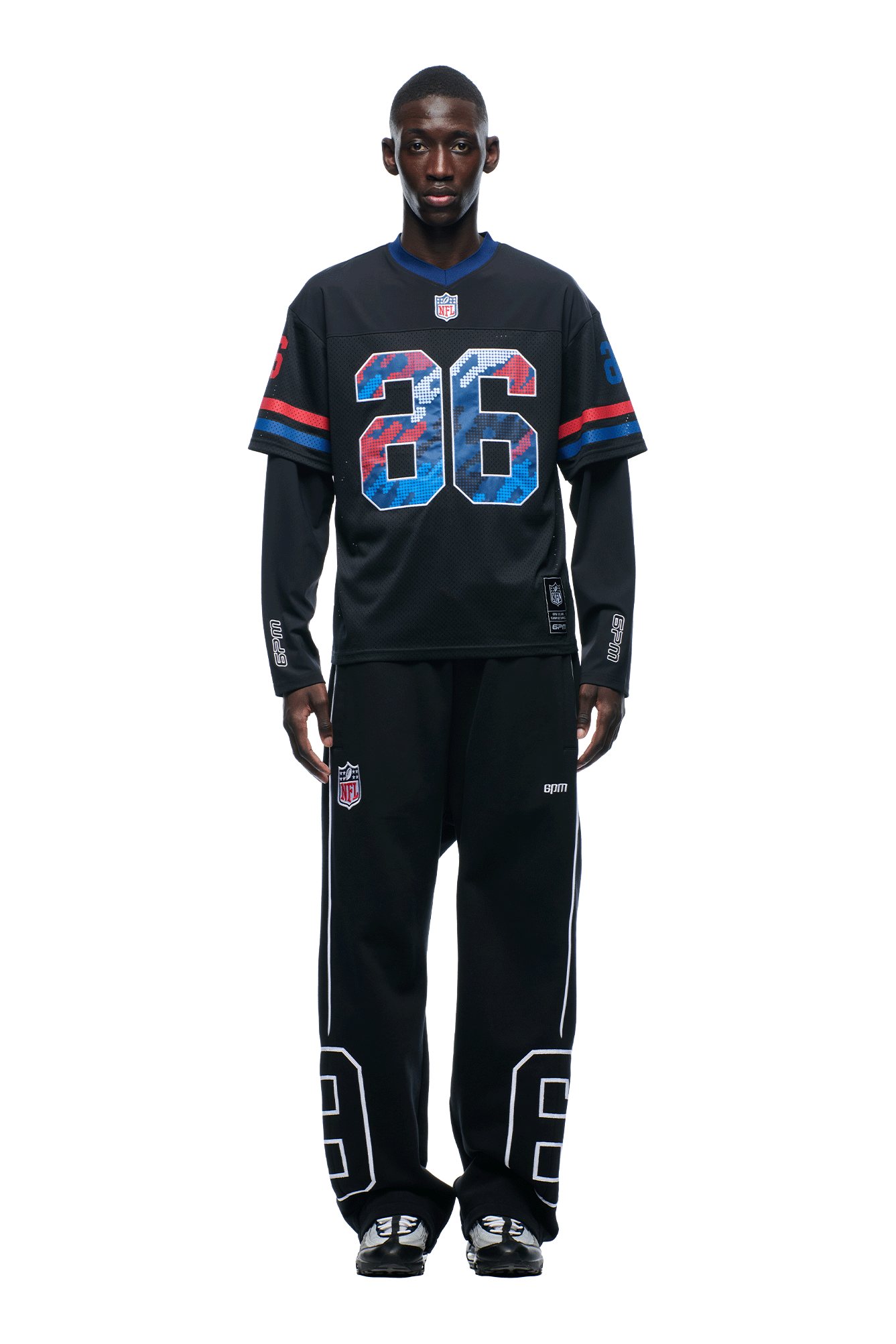 A man faces forward wearing the 6PM NFL LAYERED MESH LONGSLEEVE BLACK jersey, featuring blue, red, and white number 36, paired with black pants with bold white numbers and black sneakers, set against a plain white background.