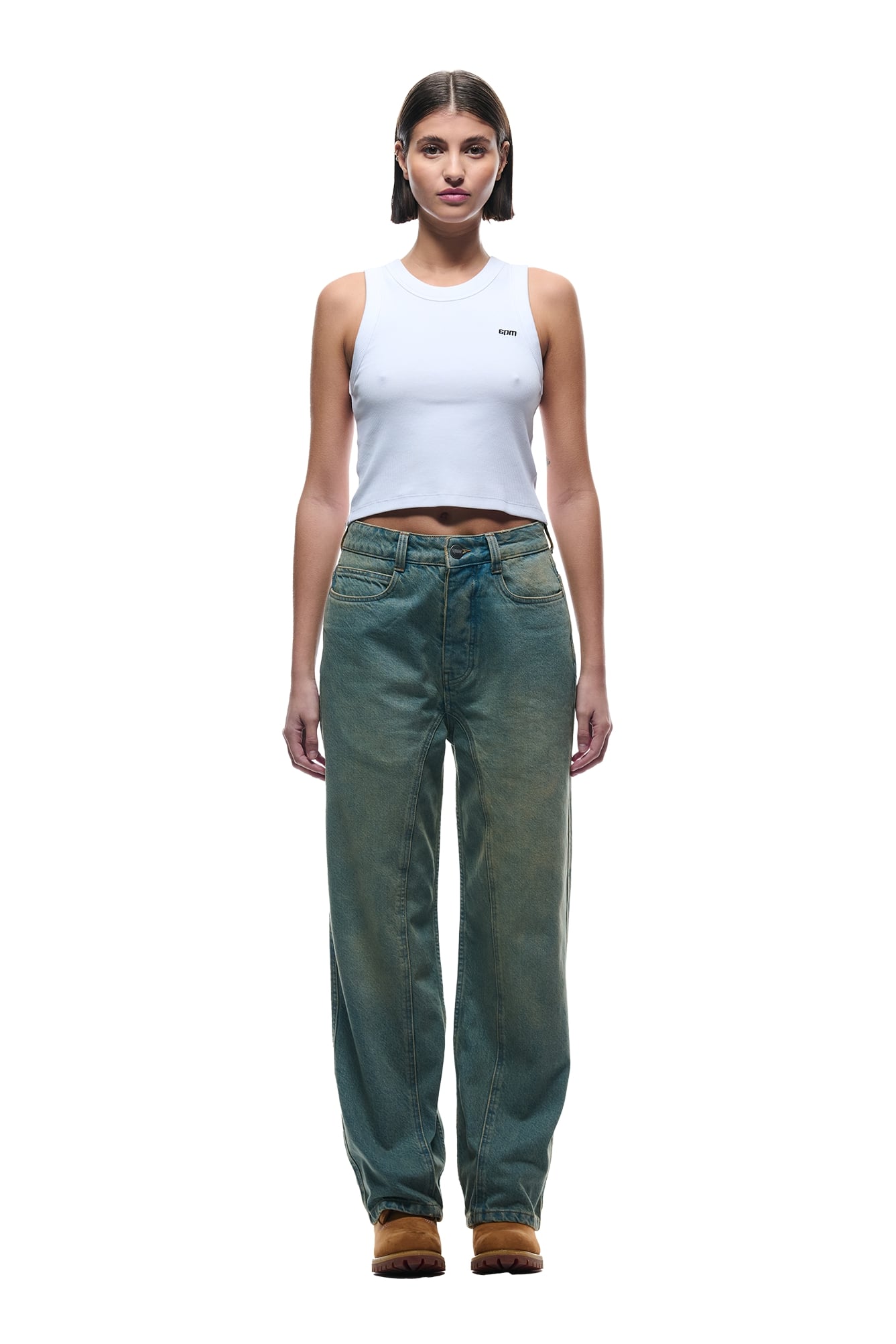 A woman faces forward in a white sleeveless crop top, 6PM CENTER SEAM DENIM LIGHT WASH jeans, and brown shoes, standing against a plain white background.