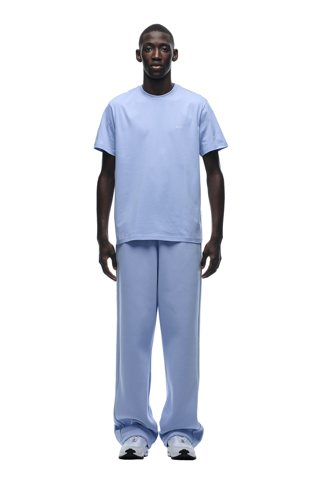 A man faces forward, wearing a 6PM T-SHIRT REGULAR FIT SOFT VIOLET with matching wide-leg pants and white sneakers. He has a neutral expression and stands against a plain, transparent background.