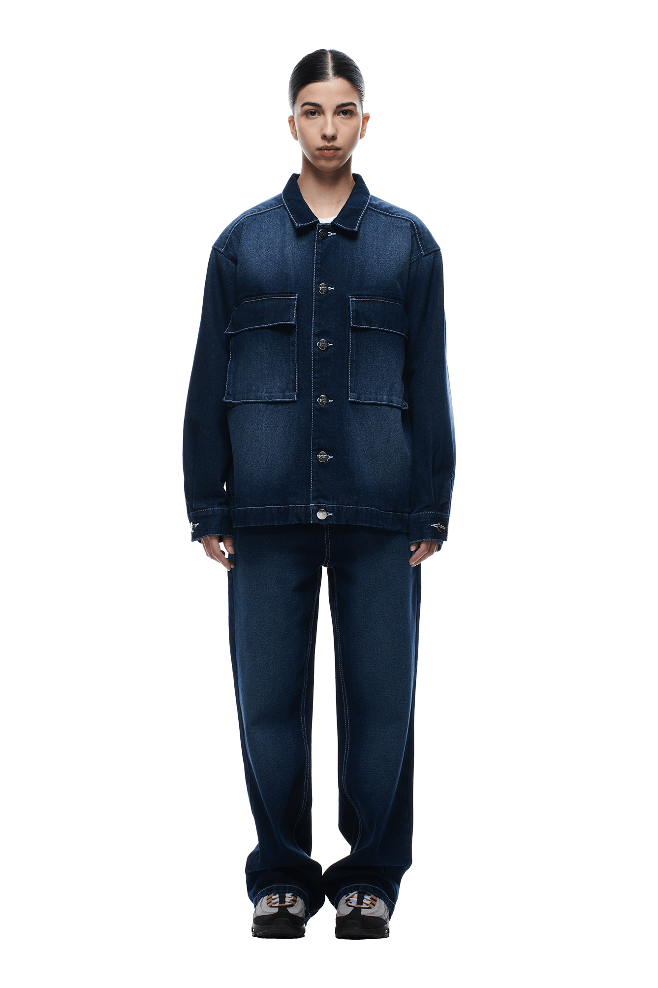 A person faces forward in a 6PM SCRIPT LOGO DENIM JACKET DARK BLUE with large front pockets and matching wide-leg jeans. They have dark hair pulled back, chunky black shoes, and stand against a plain white background.