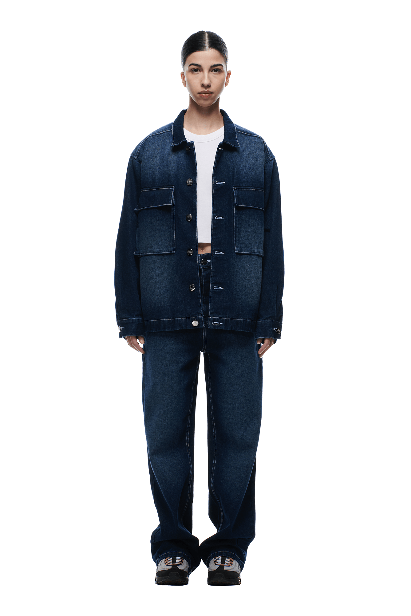 A person faces forward against a plain white background, wearing the 6PM SCRIPT LOGO DENIM JACKET DARK BLUE and matching wide-leg jeans, styled with a white crop top and black sneakers.