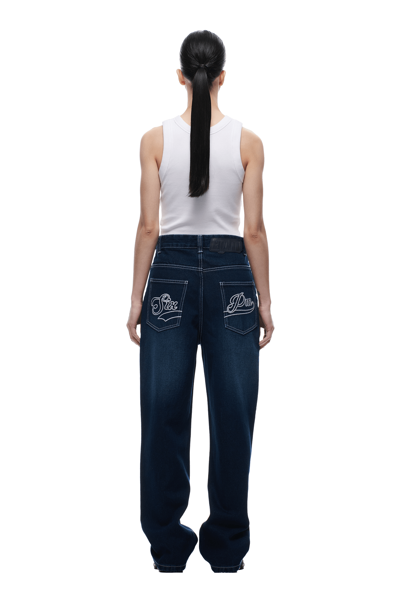 A person with long black hair in a ponytail, wearing a white sleeveless top and 6PM's SCRIPT LOGO DENIM WASHED DARK BLUE jeans, stands facing away against a plain white background.