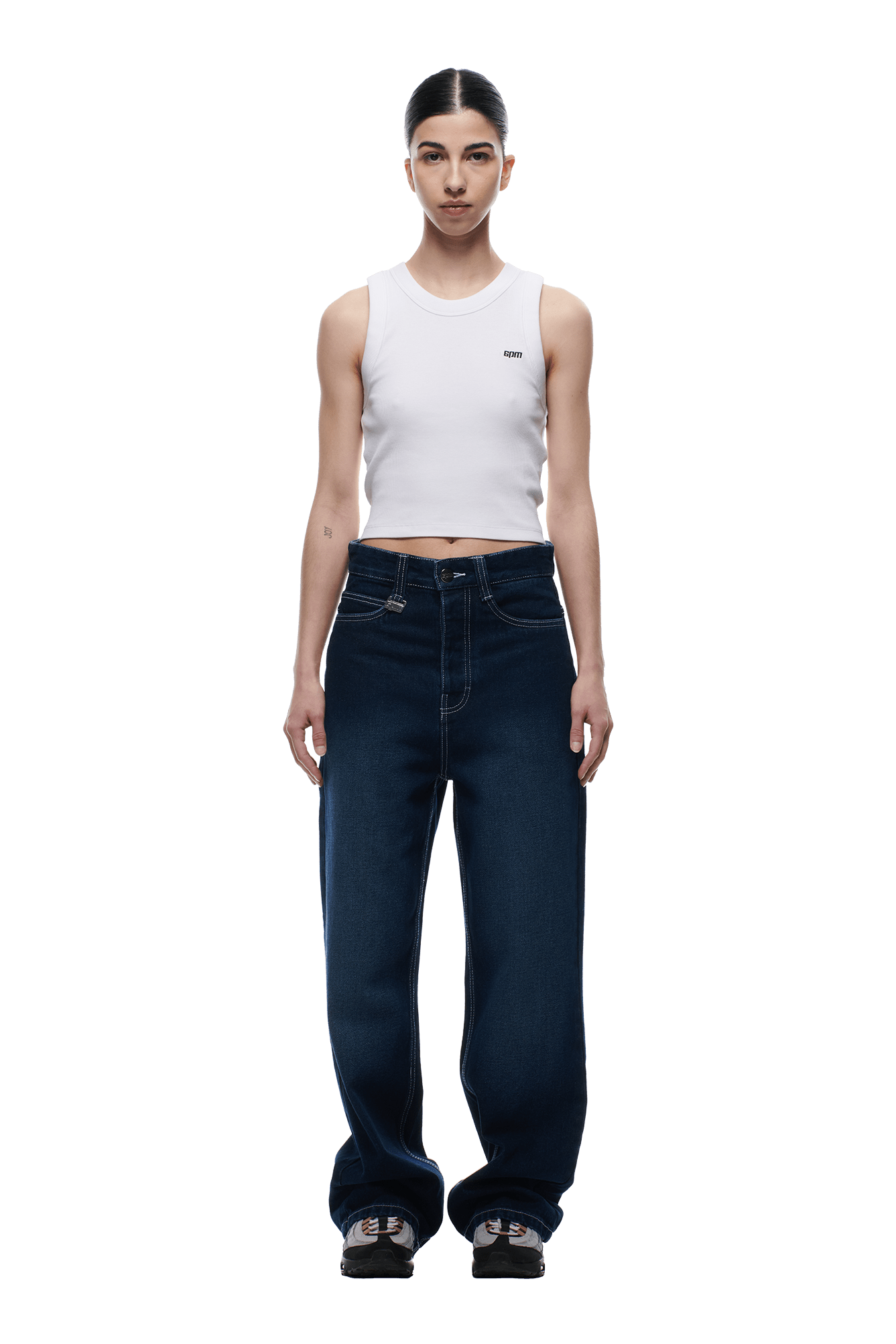 A person stands facing forward against a plain white background, wearing a white sleeveless crop top, black sneakers, and 6PM SCRIPT LOGO DENIM WASHED DARK BLUE jeans.