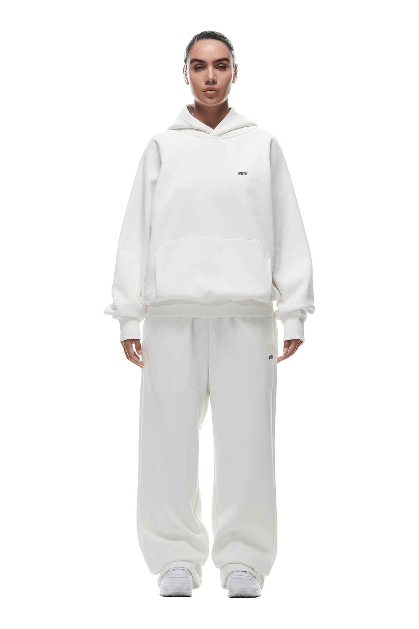 A person faces forward wearing the 6PM HOODIE COCONUT WHITE with raglan sleeves, a kangaroo pocket, and matching wide-leg sweatpants paired with white sneakers. Ideal for daily wear. Background is transparent.