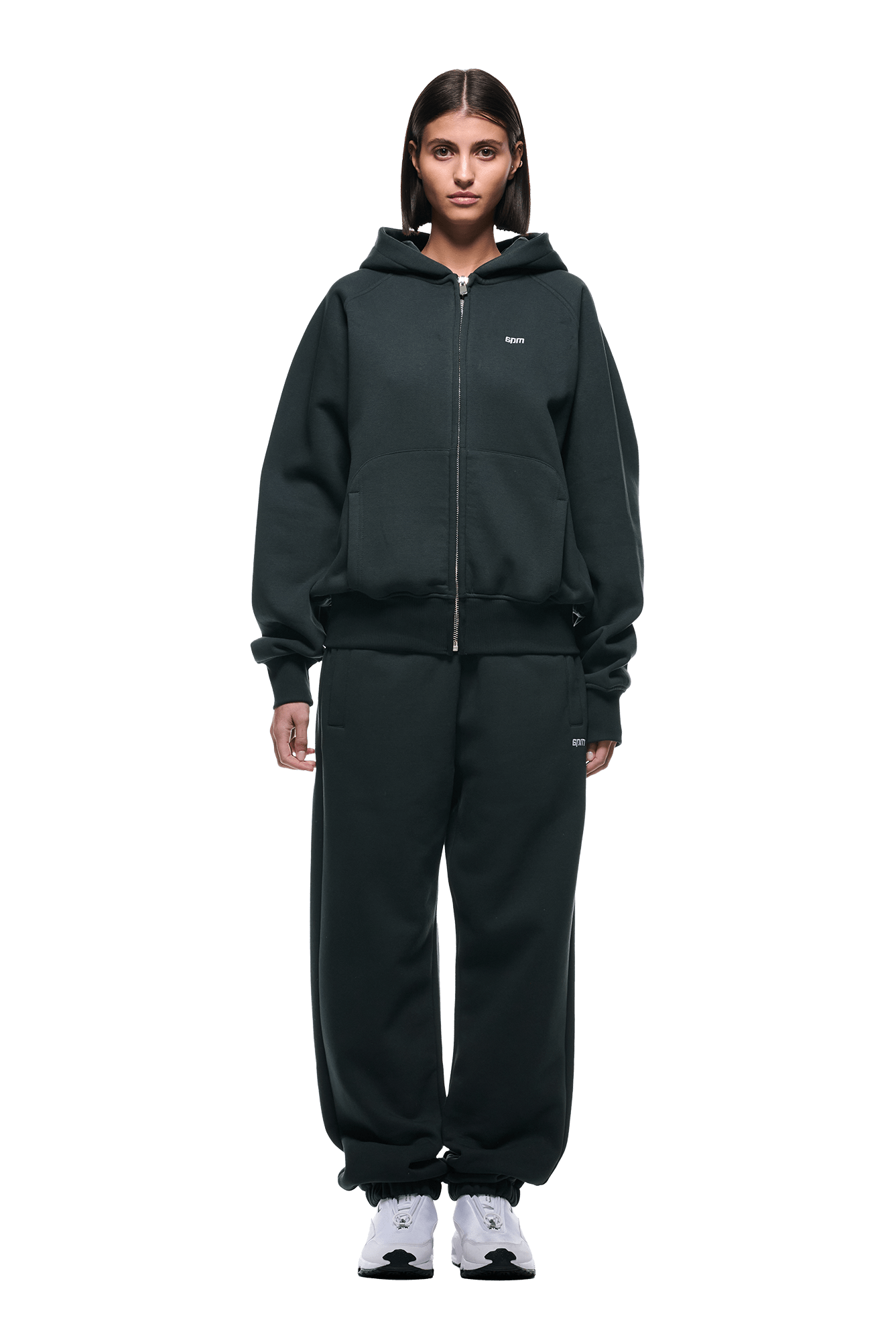 A person faces forward wearing the 6PM ZIP HOODIE DARK EMERALD and matching pants with white sneakers. This clean, everyday outfit is shown on a transparent background.