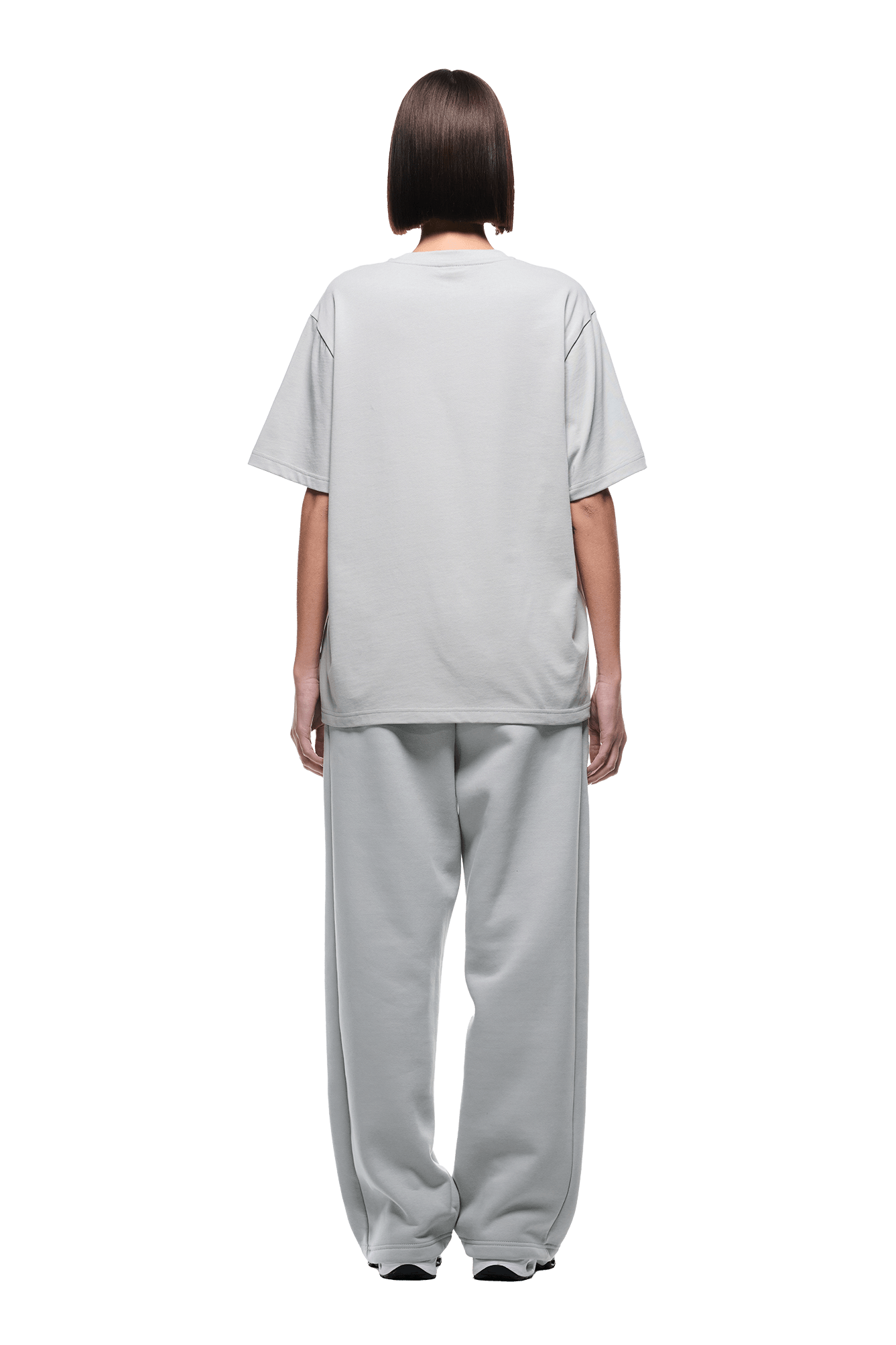 A person with a straight bob stands facing away, wearing the 6PM T-SHIRT SMOKE GREY and matching wide-leg pants on a transparent background.