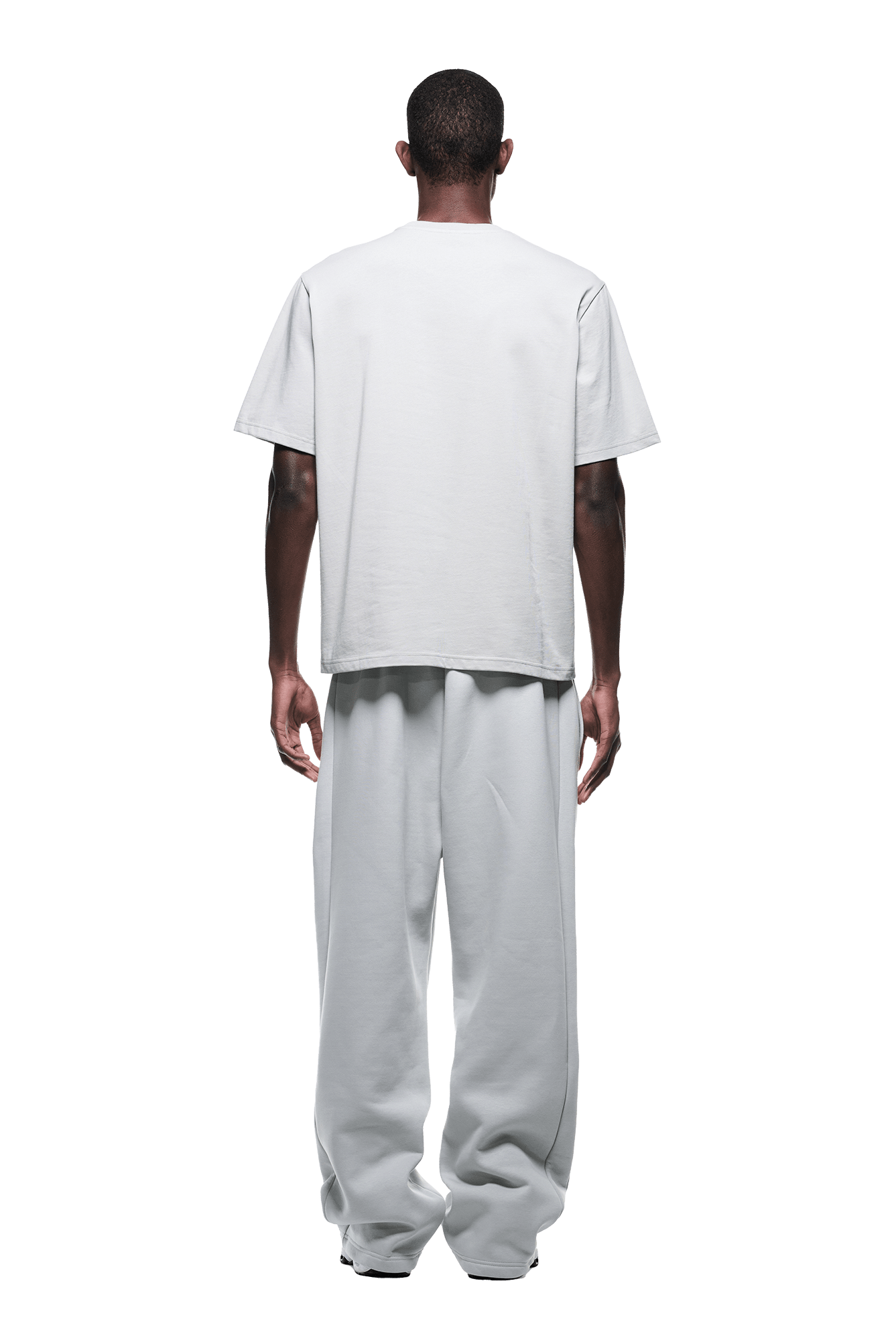 A person faces away from the camera, dressed in the 6PM T-SHIRT SMOKE GREY paired with matching wide-leg pants, set against a plain green background.