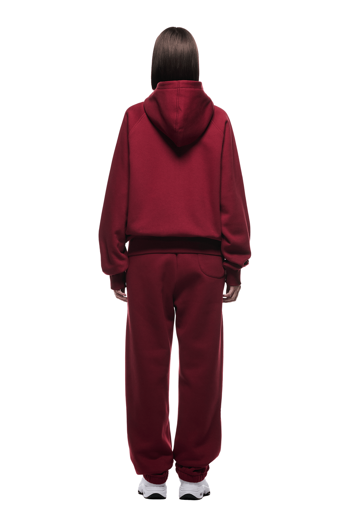 Seen from behind, a person with straight brown hair wears the 6PM ZIP HOODIE WINE RED and matching sweatpants with white sneakers—a cozy yet structured everyday look against a plain background.