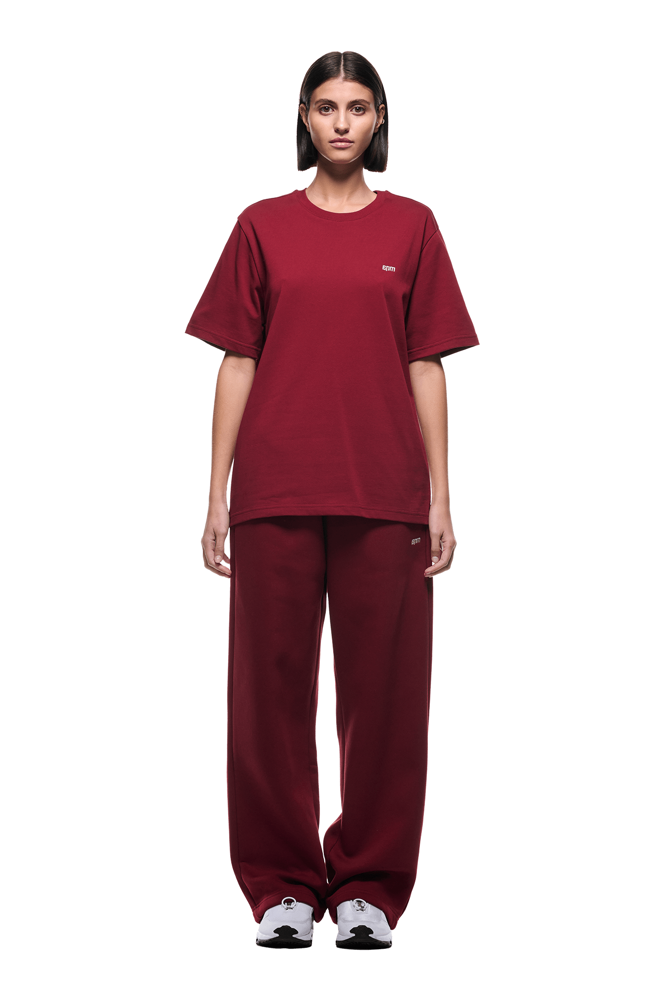 A person stands facing forward, wearing a loose-fit 6PM T-SHIRT WINE RED with matching wide-leg pants and white sneakers. The background is transparent.