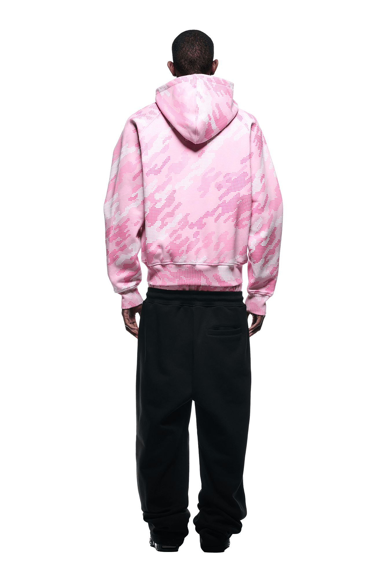 A person faces away, wearing the 6PM DOT CAMO ZIP HOODIE PINK—a pink and white digital camo hoodie—paired with loose black pants, all set against a plain white background.