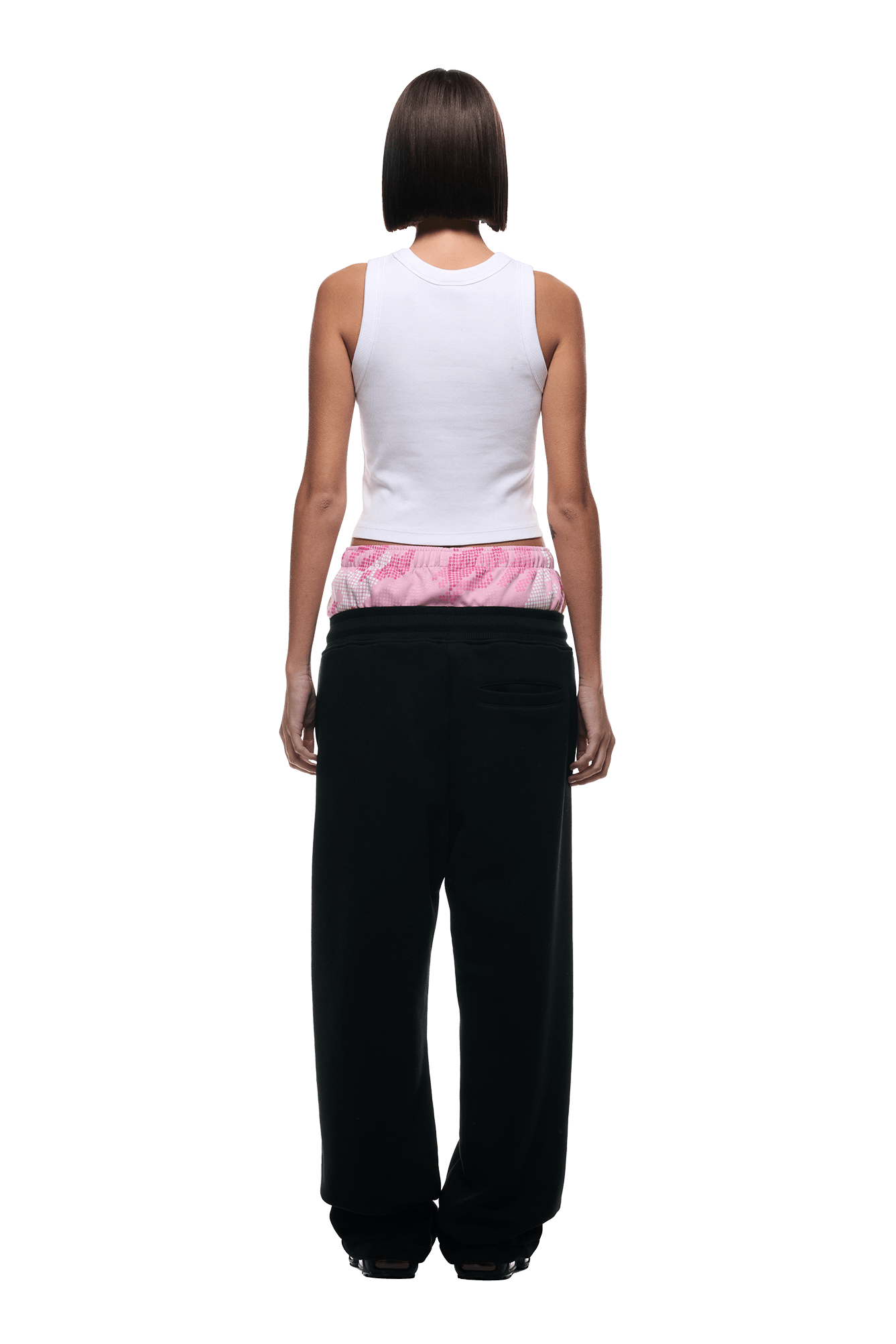 A person with a straight bob haircut is seen from behind wearing a white sleeveless top, 6PM’s BOXERS OPEN LEG JOGGER BLACK pants, and pink-and-white waistband underwear showing above the joggers.