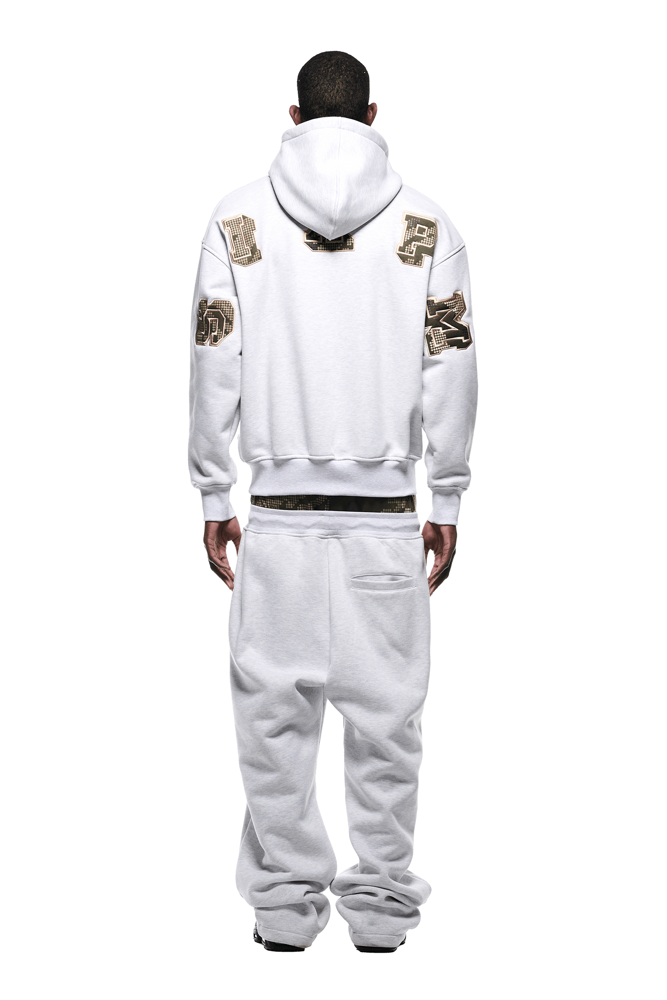 A man faces away, wearing the 6PM DOT CAMO LETTER HOODIE GREY with matching baggy sweatpants. The oversized look stands out against a plain white background.