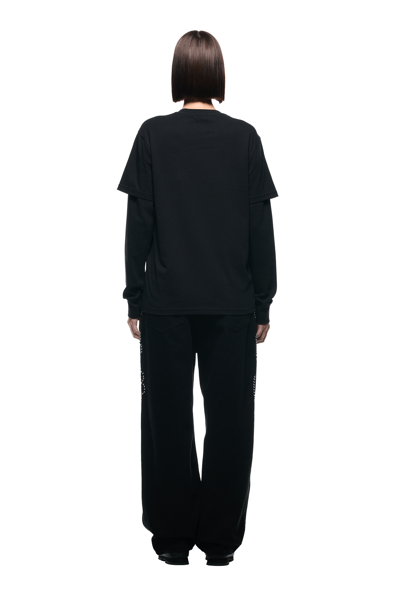 A person with straight, chin-length brown hair stands facing away against a white background, wearing the 6PM LAYERED LONGSLEEVE BLACK top and wide-leg black pants.