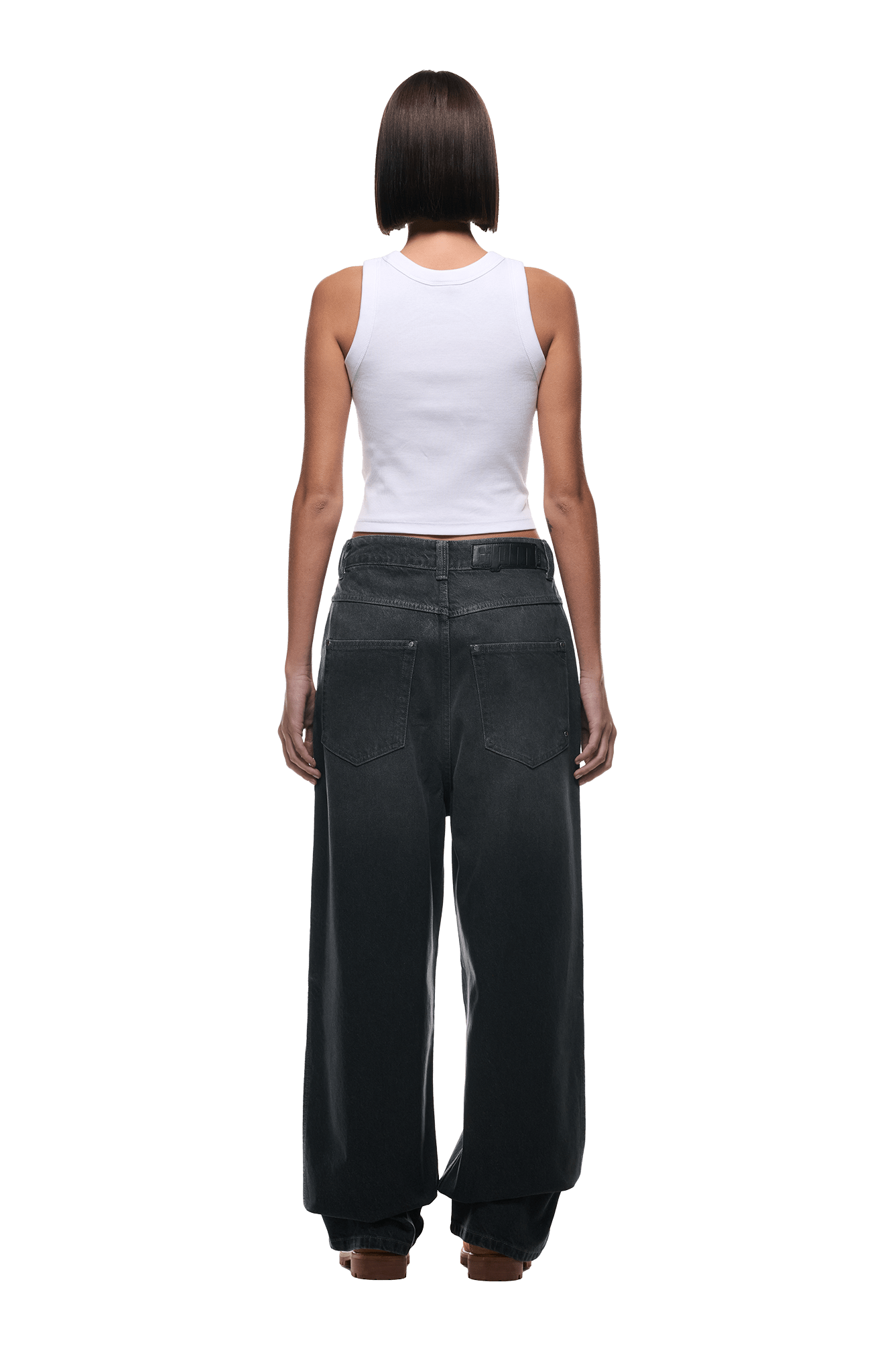 A person with short, straight hair faces away, wearing a white sleeveless tank top and 6PMs WAX COATED DENIM GREY jeans in a loose fit, set against a plain white background.