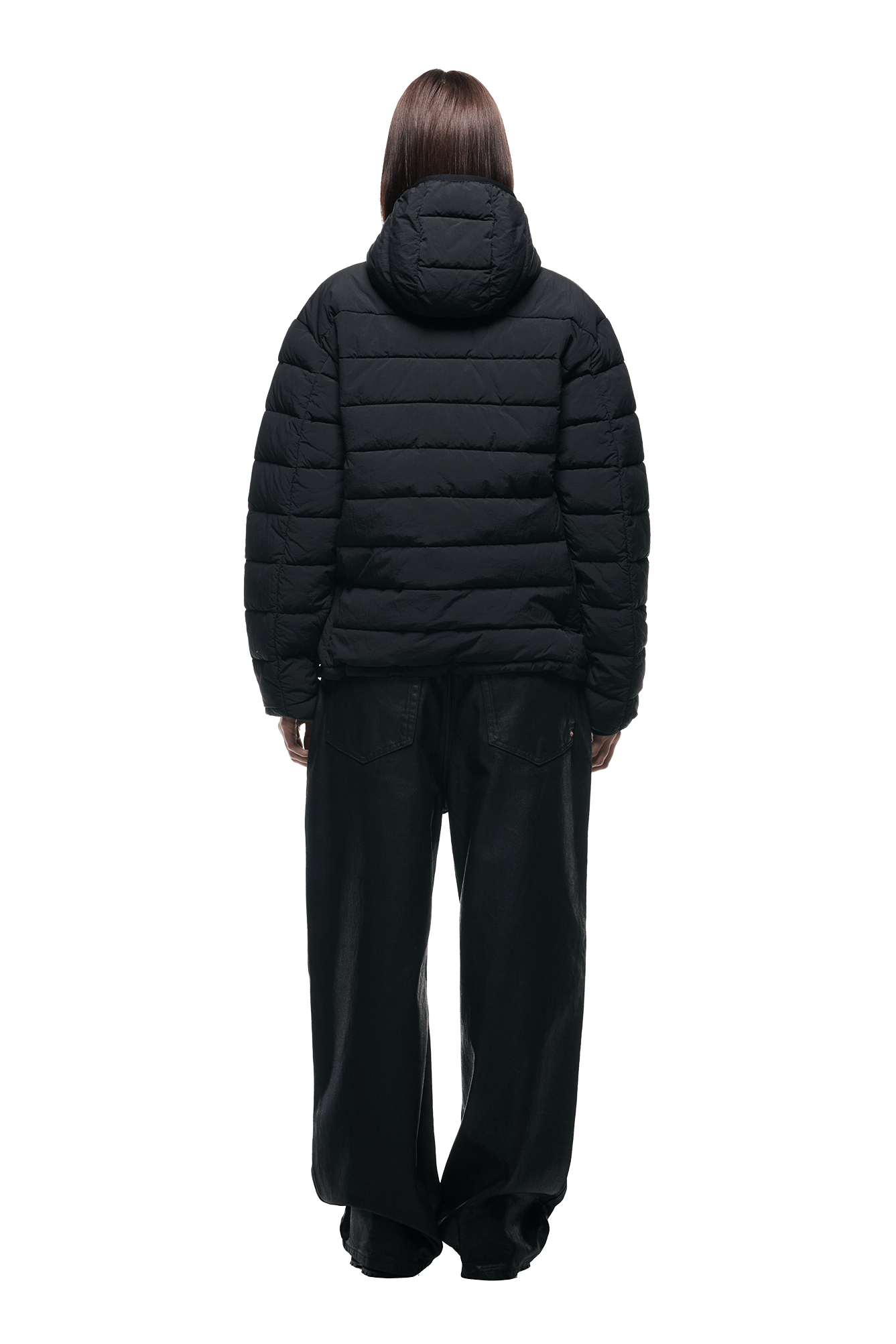 A person with straight, dark hair stands with their back to the camera, wearing the 6PM LIGHT PUFFER JACKET BLACK and loose-fitting black pants against a plain white background.