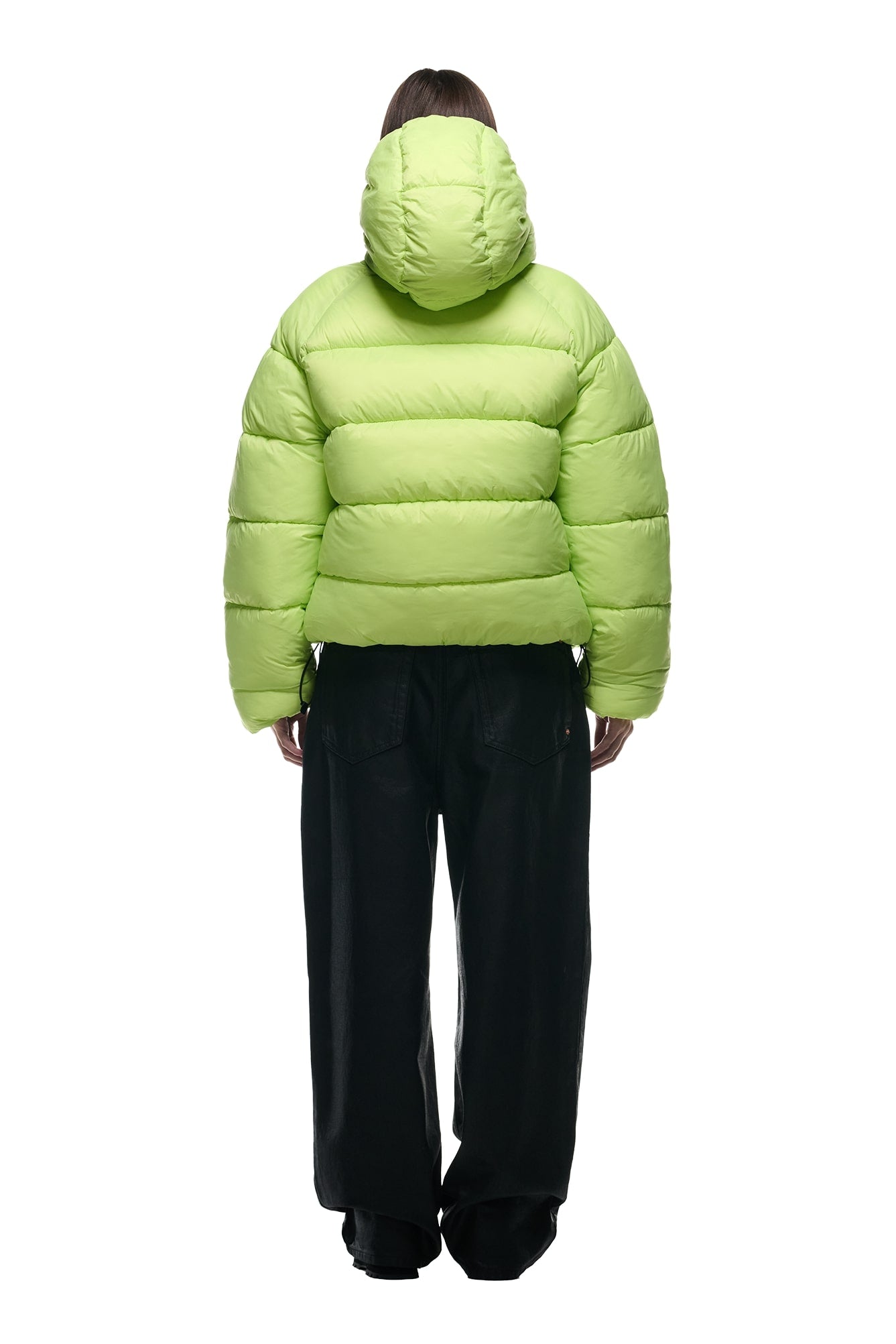 A person facing away wears the 6PM REVERSIBLE PUFFER JACKET BLACK with a hood and loose black pants against a plain white background.