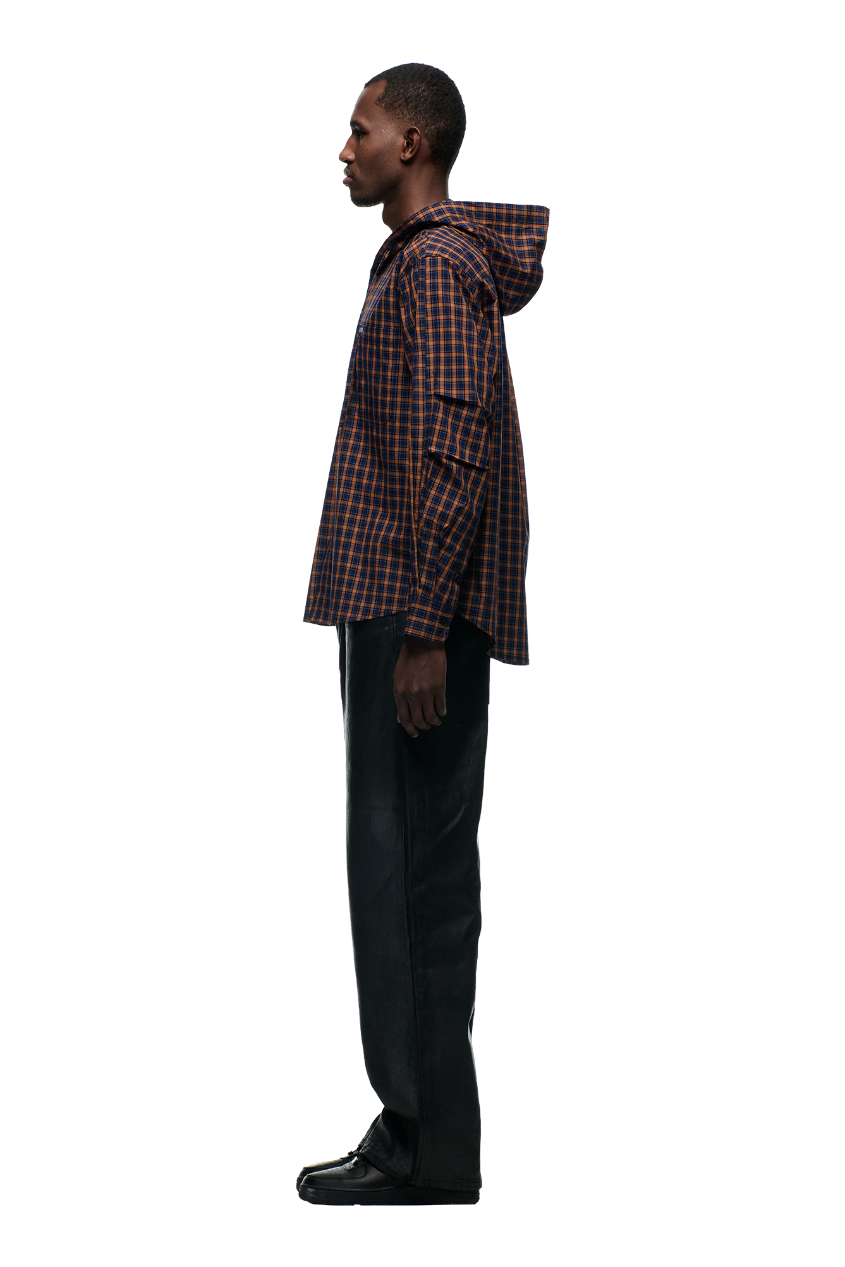 A man stands in profile wearing the 6PM HOODED DRESS SHIRT in blue, orange, and black, paired with black pants and shoes, against a plain white background.