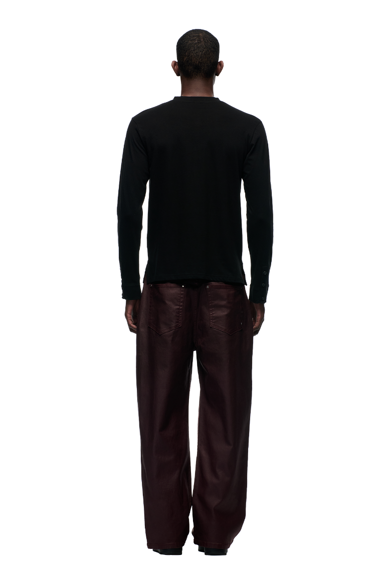 A person stands facing away, wearing the 6PM BUTTONED SLIM FIT LS BLACK shirt with subtle sleeve details and loose-fitting dark burgundy pants against a plain light background.